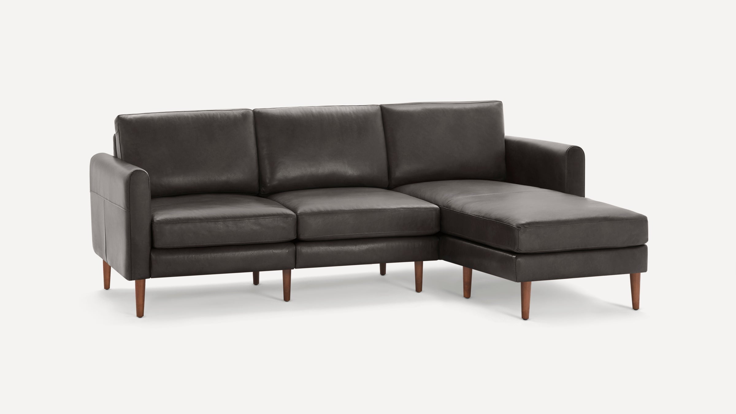 Dark gray leather sectional sofa with mid-century wooden legs, featuring a chaise on the right side and clean, modern lines.