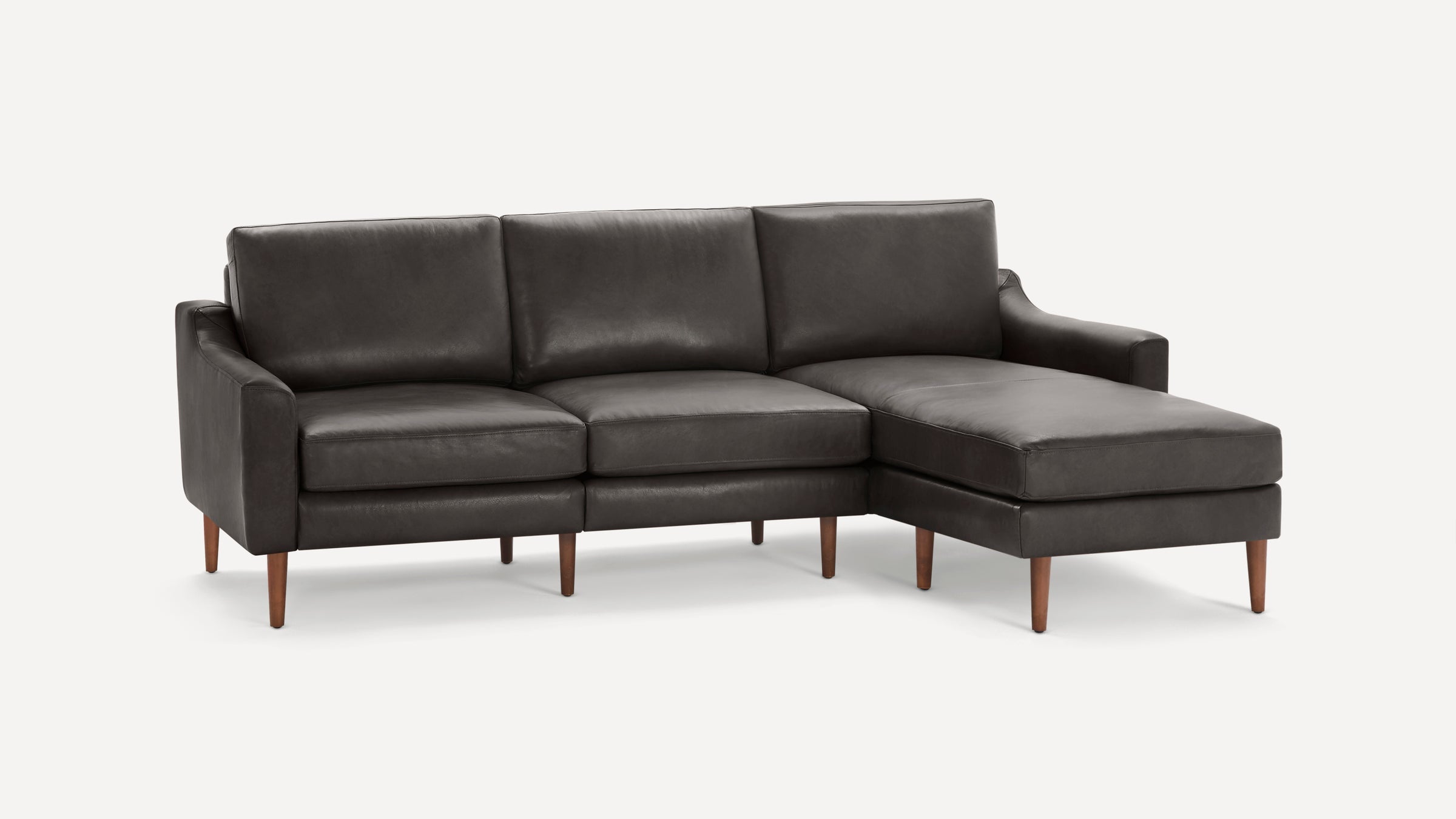 Dark gray leather sectional sofa with three cushions, wooden tapered legs, and a chaise lounge on the right side.