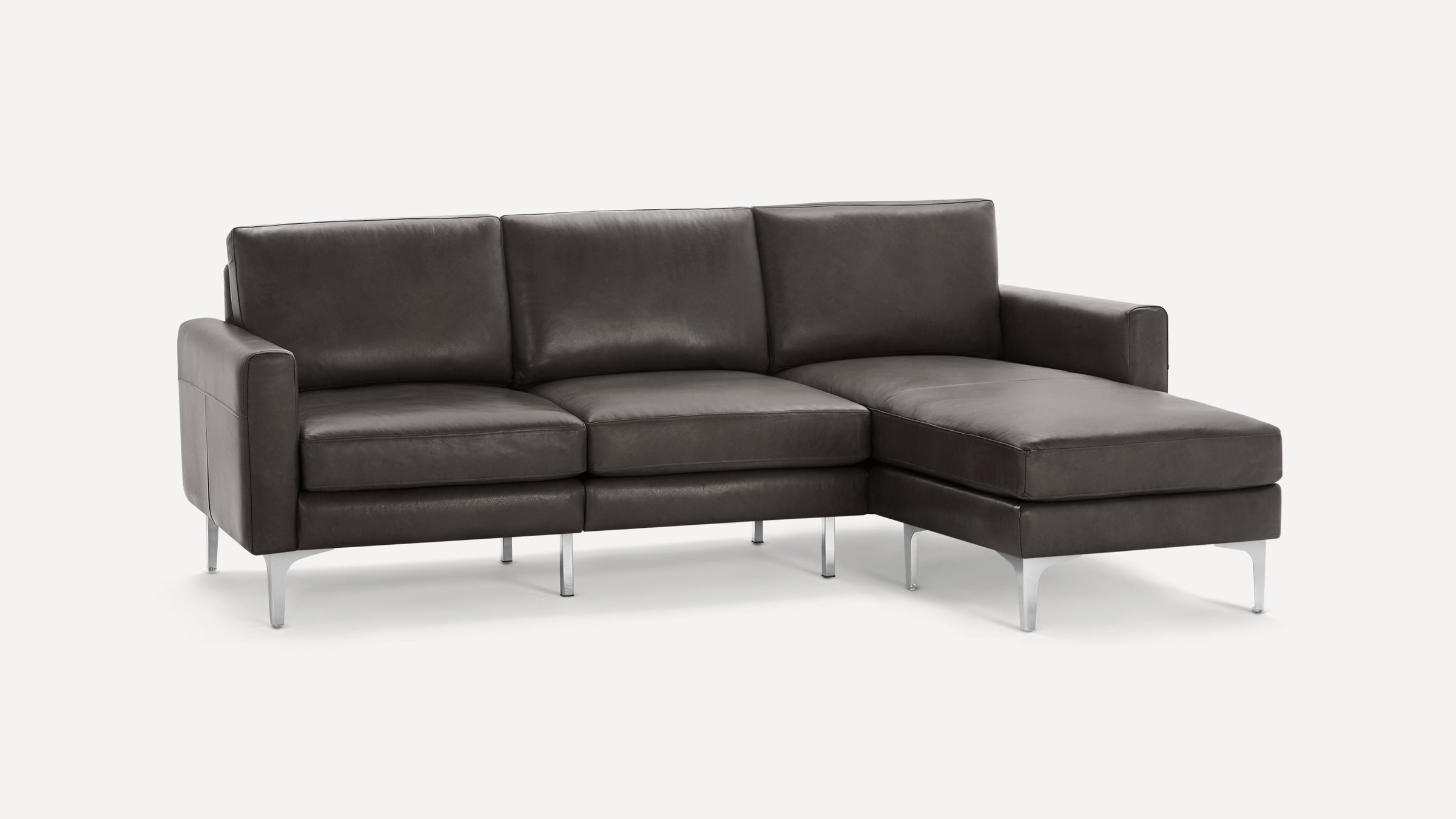 Modern dark gray leather sectional sofa with three cushions, metal legs, and a chaise lounge on the right side.