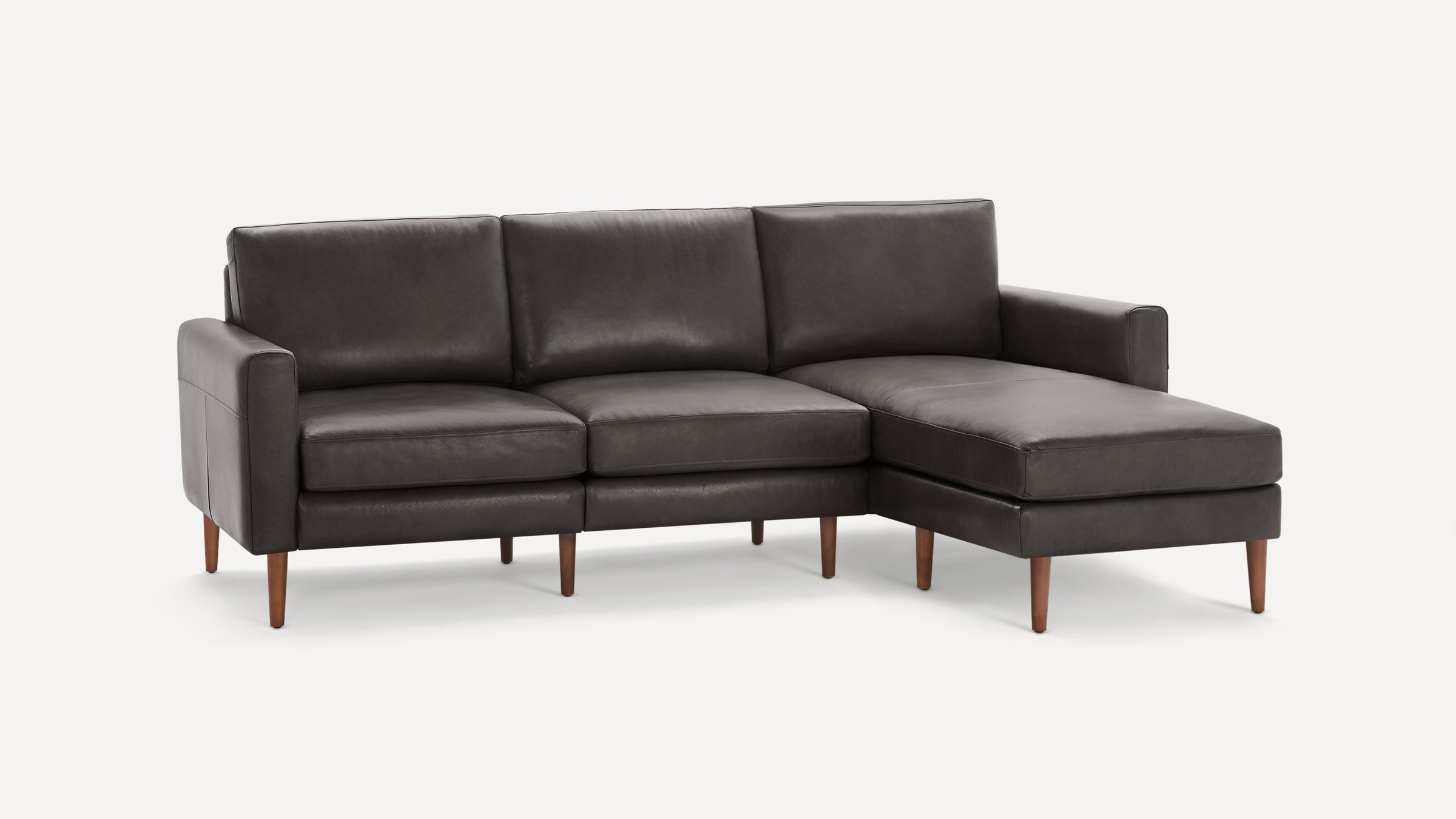 Dark gray leather sectional sofa with wooden tapered legs and a right-side chaise lounge on a white background.