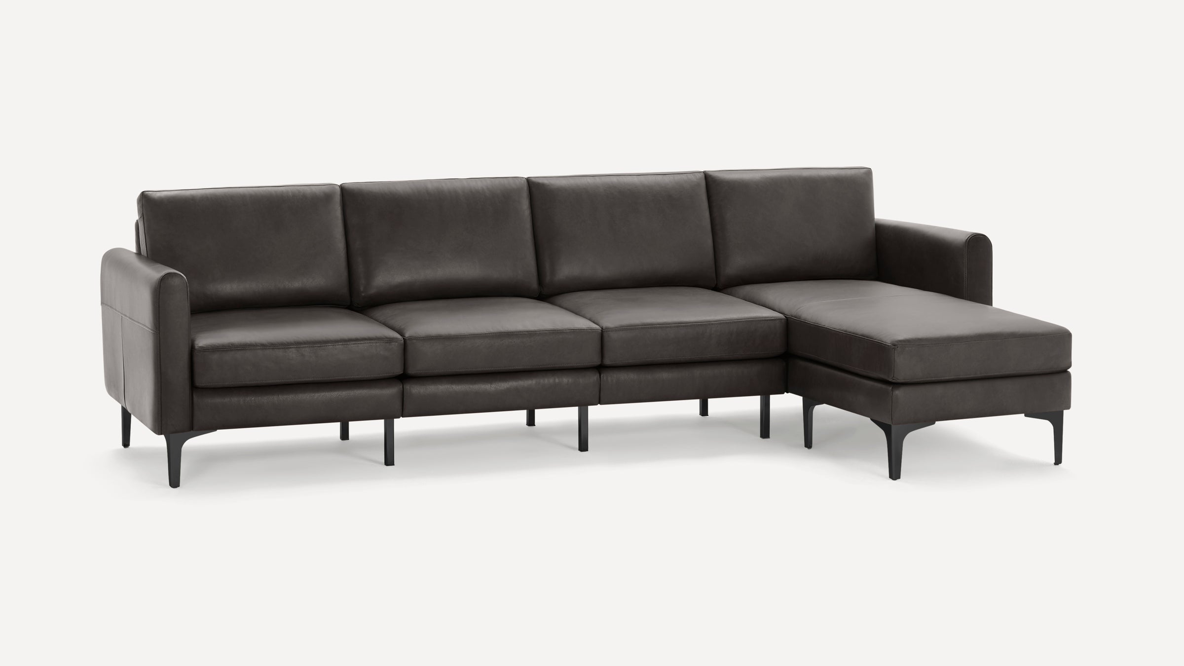 Modern dark gray leather sectional sofa with cushioned seats, backrests, armrests, and slender black legs.