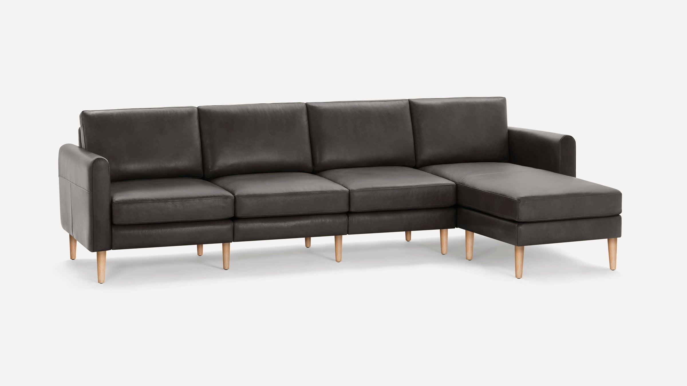 Dark gray leather sectional sofa with chaise, featuring wooden legs and clean, modern design.