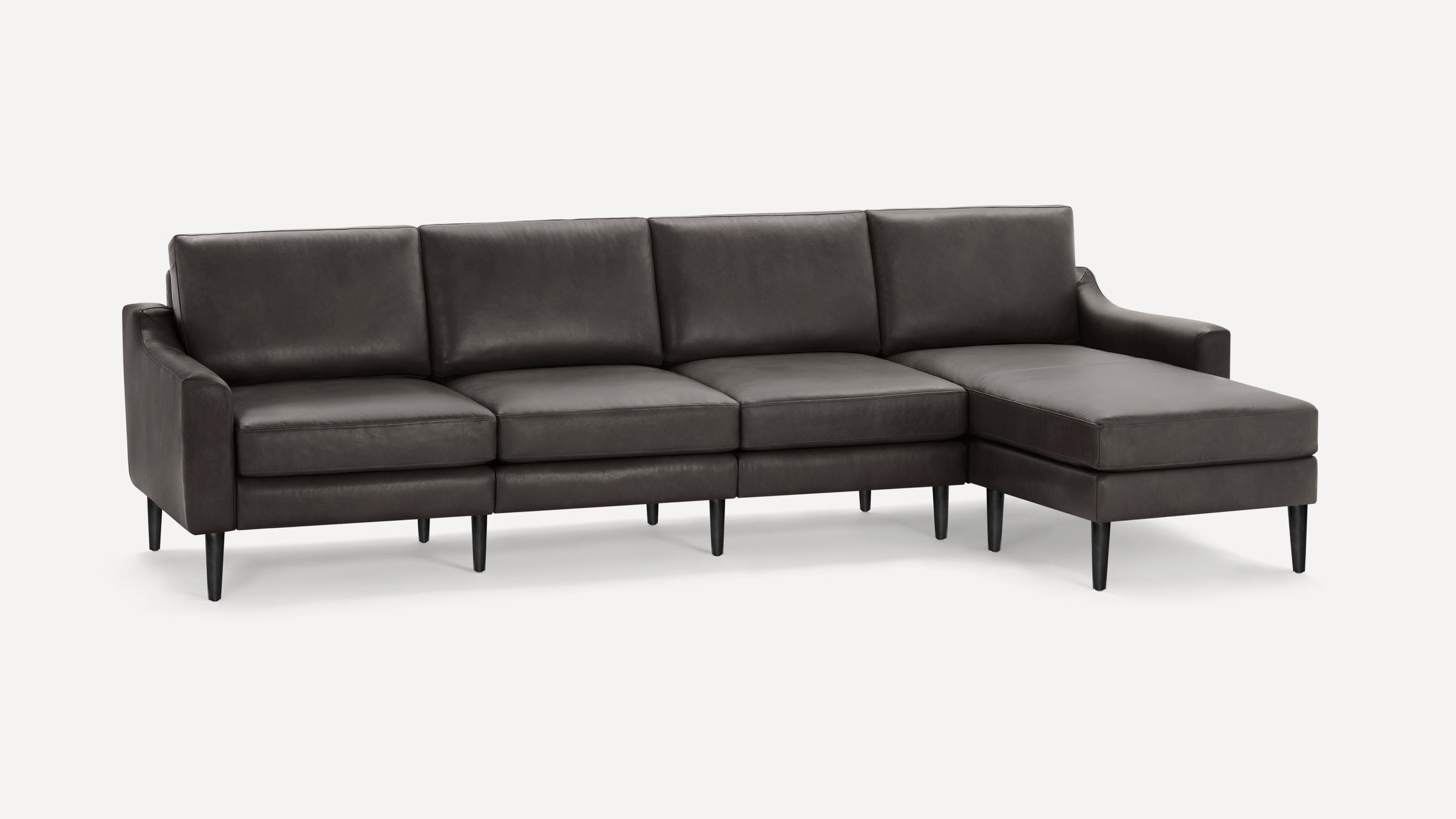 Modern sectional sofa with dark gray leather upholstery, tapered black legs, and chaise on the right side.