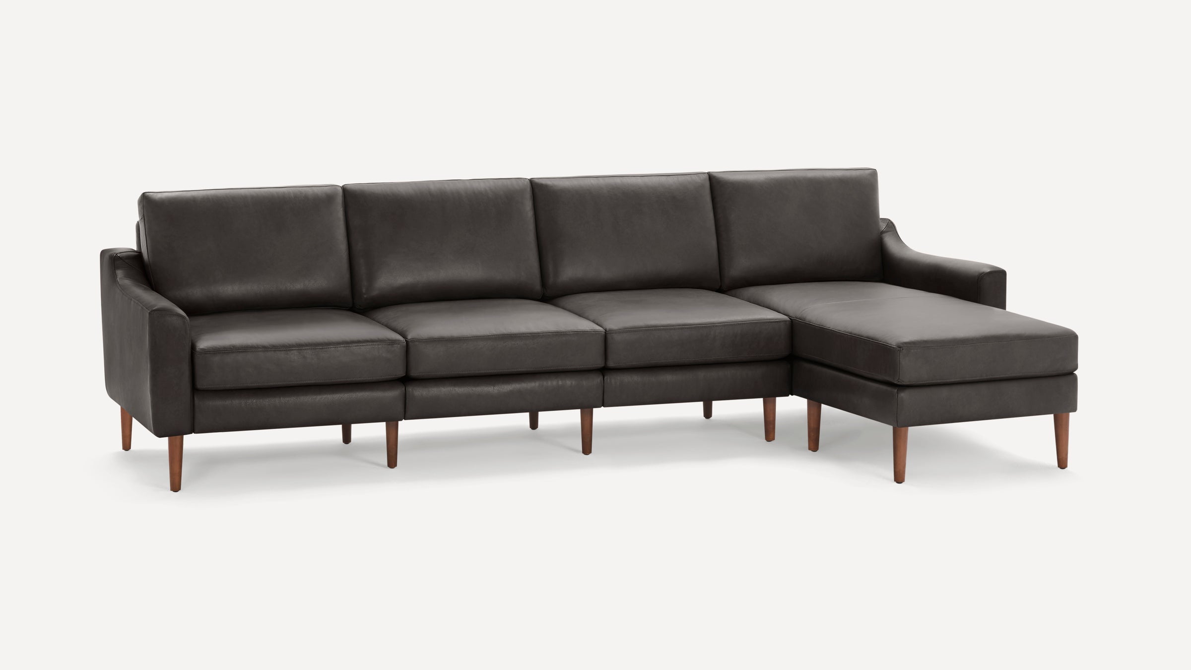 Modern dark gray leather sectional sofa with wooden tapered legs and chaise lounge on right side.
