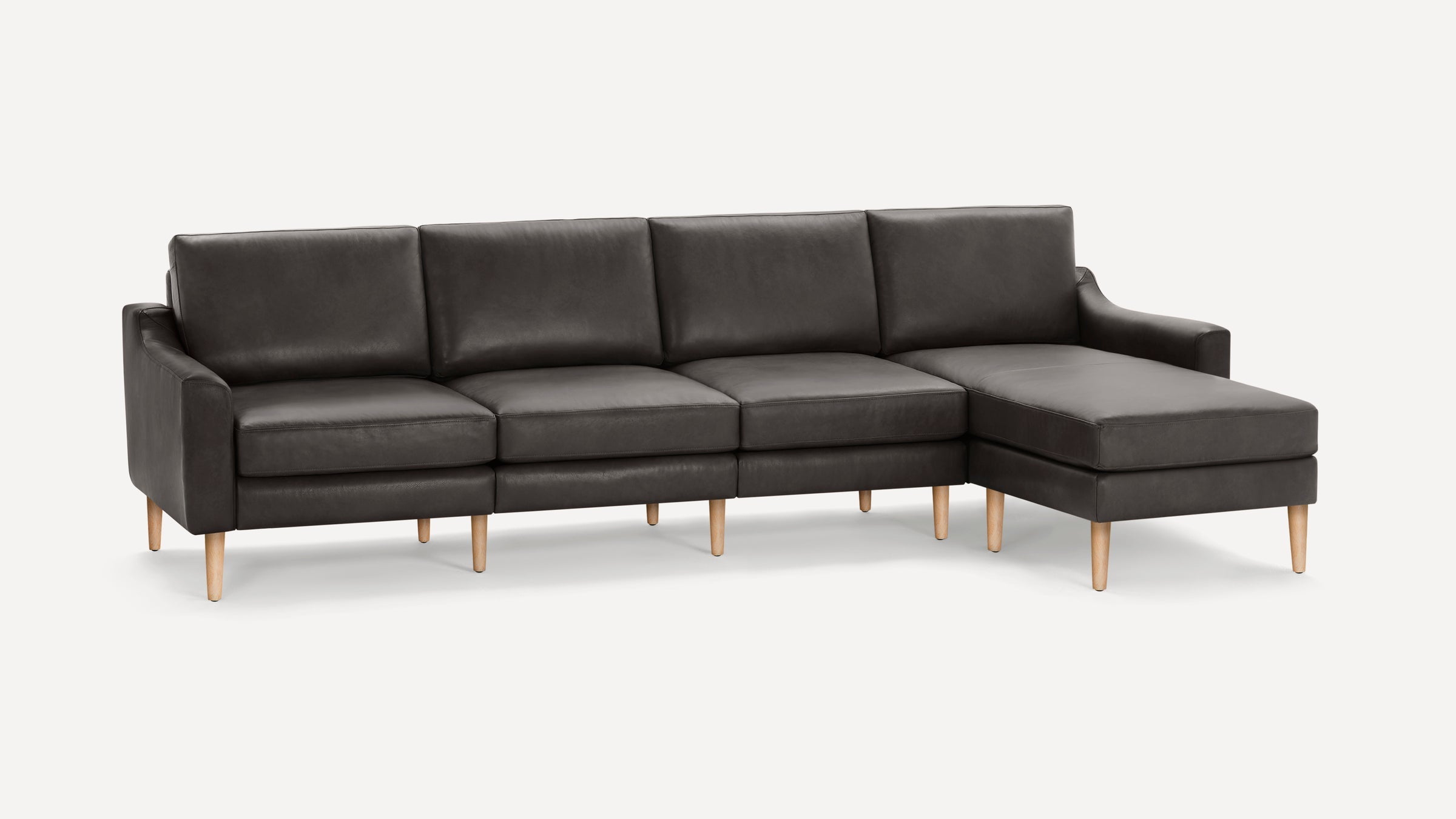 Dark gray leather sectional sofa with wooden legs and a chaise lounge on the right side, modern and minimalist design.