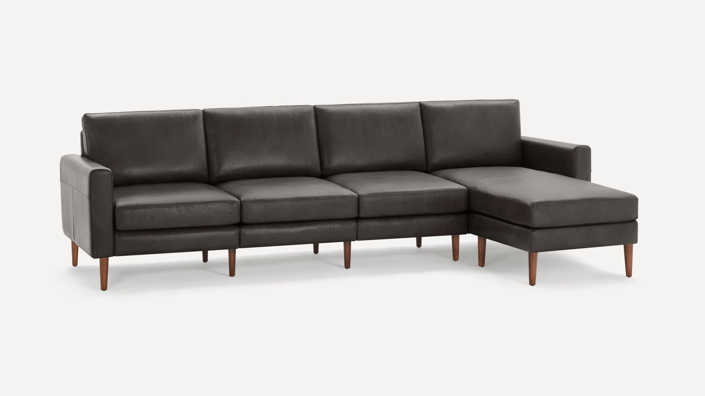 Dark gray leather sectional sofa with wooden legs, featuring three seats and a chaise lounge on the right side.