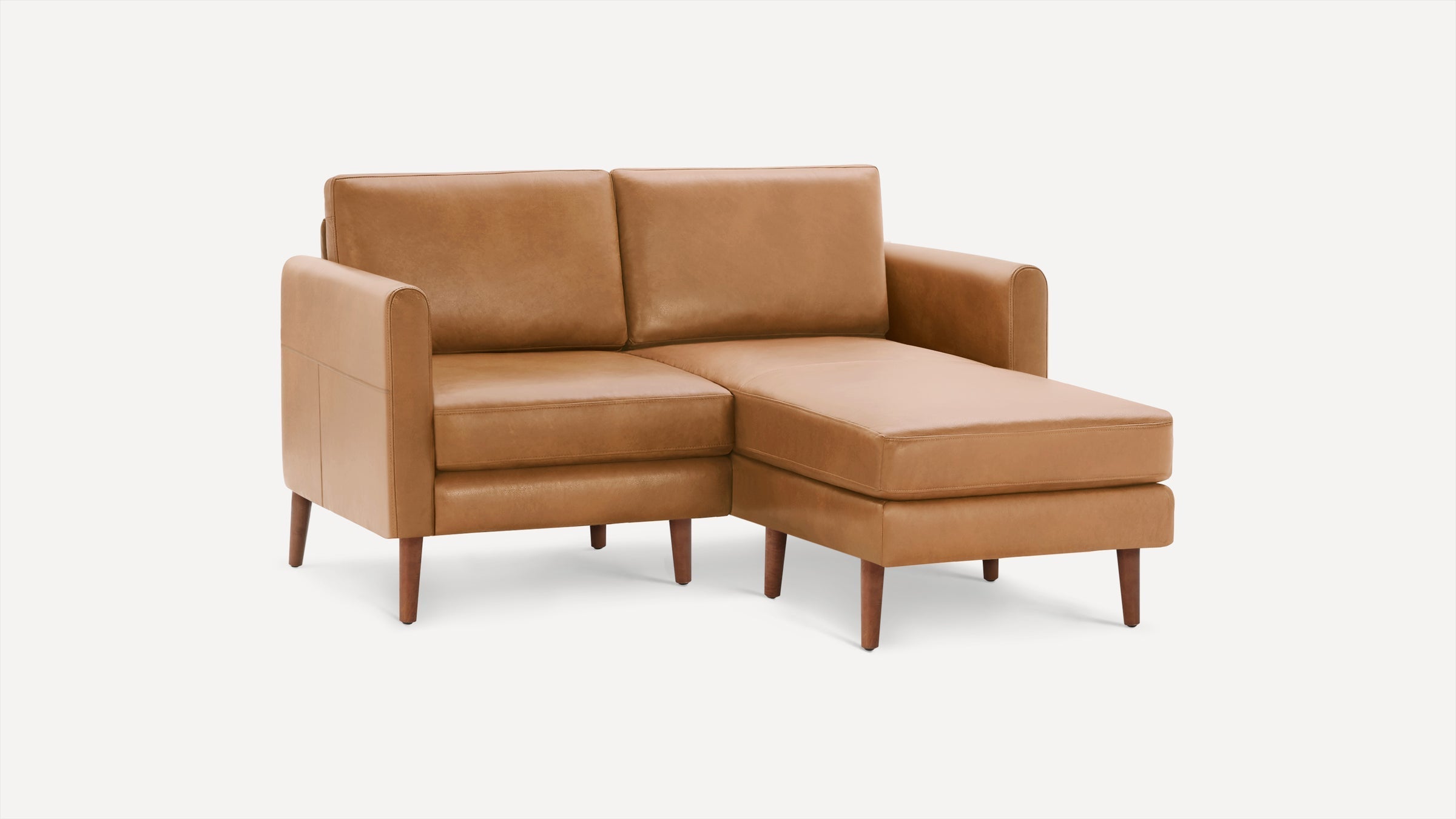 Tan leather sectional sofa with wooden legs, featuring a clean, modern design and chaise lounge extension.