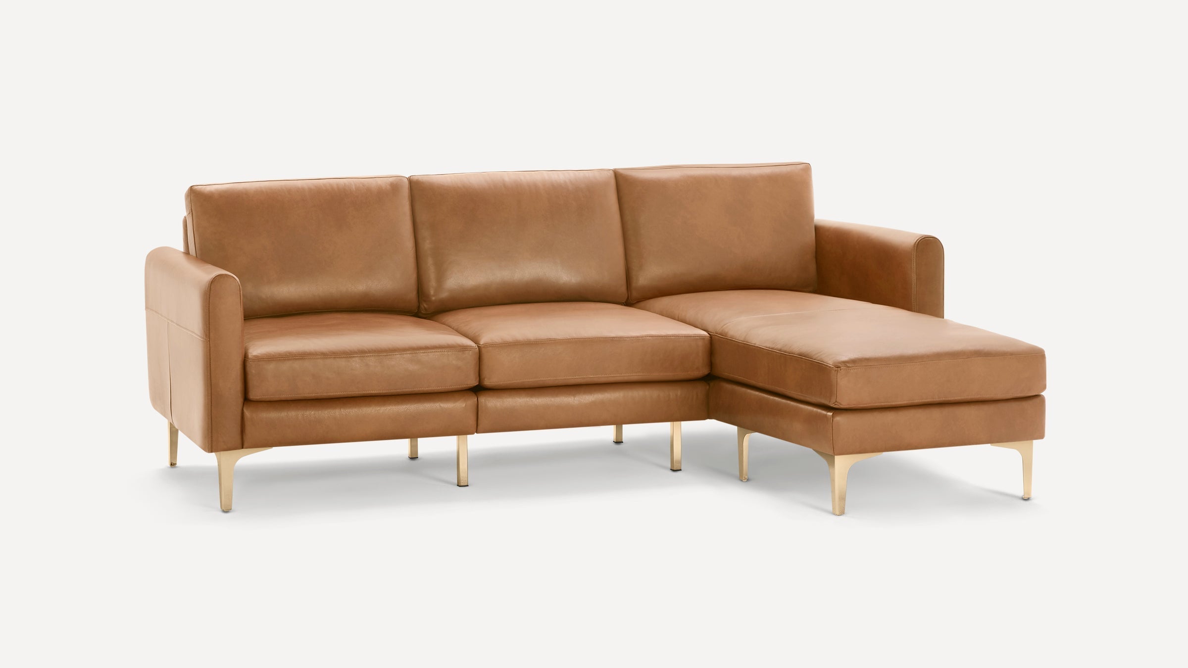 Modern L-shaped sectional sofa in light brown leather with gold metal legs, featuring three seat cushions and a chaise lounge.