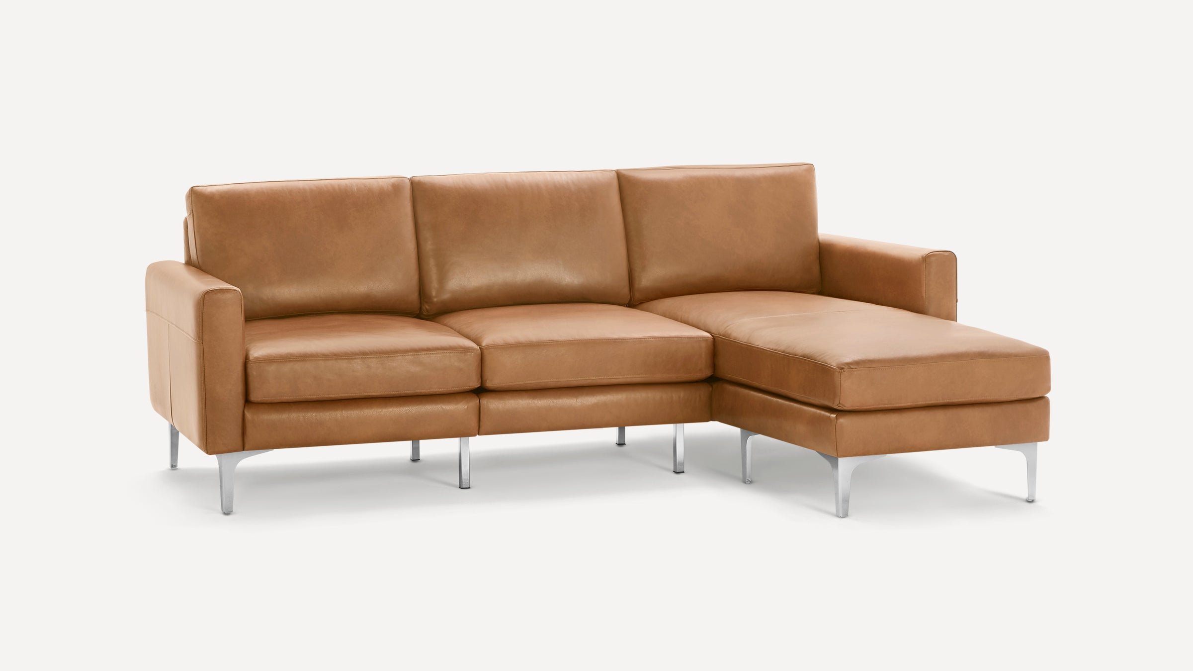 Modern tan leather sectional sofa with three seat cushions, chaise lounge on the right, and metal legs on white background.