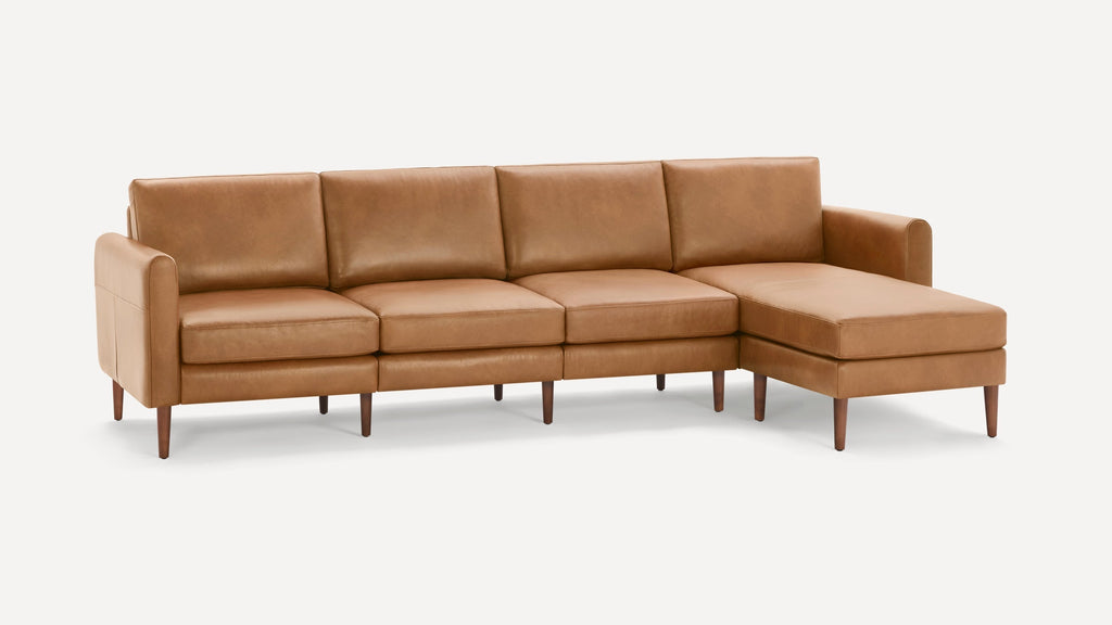 Modern tan leather sectional sofa with four seat cushions, padded armrests, and wooden legs on white background.