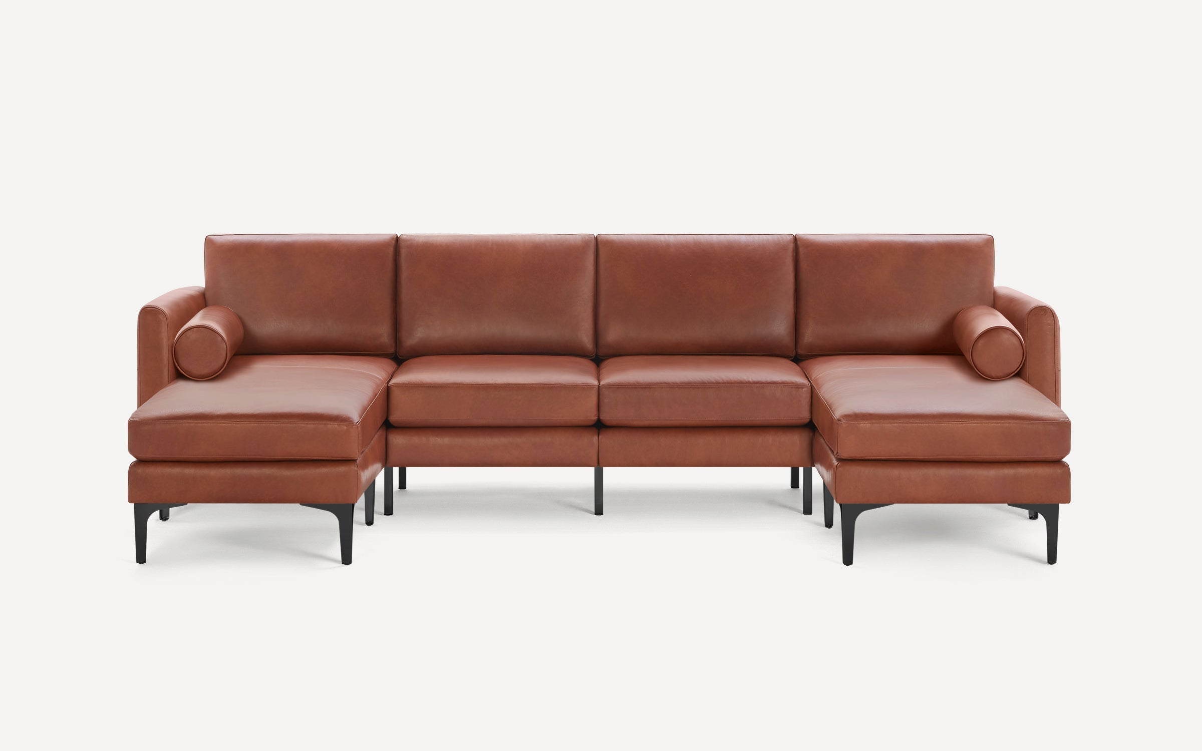 Brown leather sectional sofa with chaise lounges on both ends and slim black metal legs against white background.