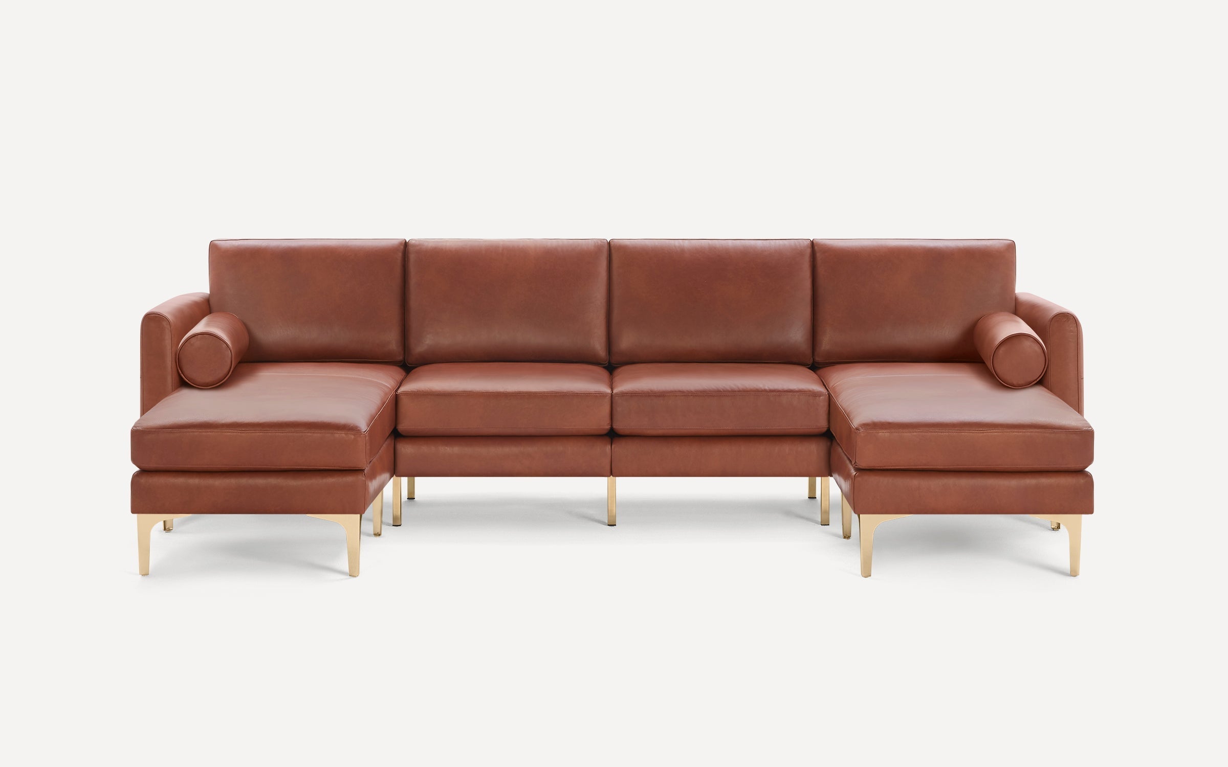 Modern brown leather sectional sofa with gold metal legs, featuring two chaise lounges and round bolsters on each end.