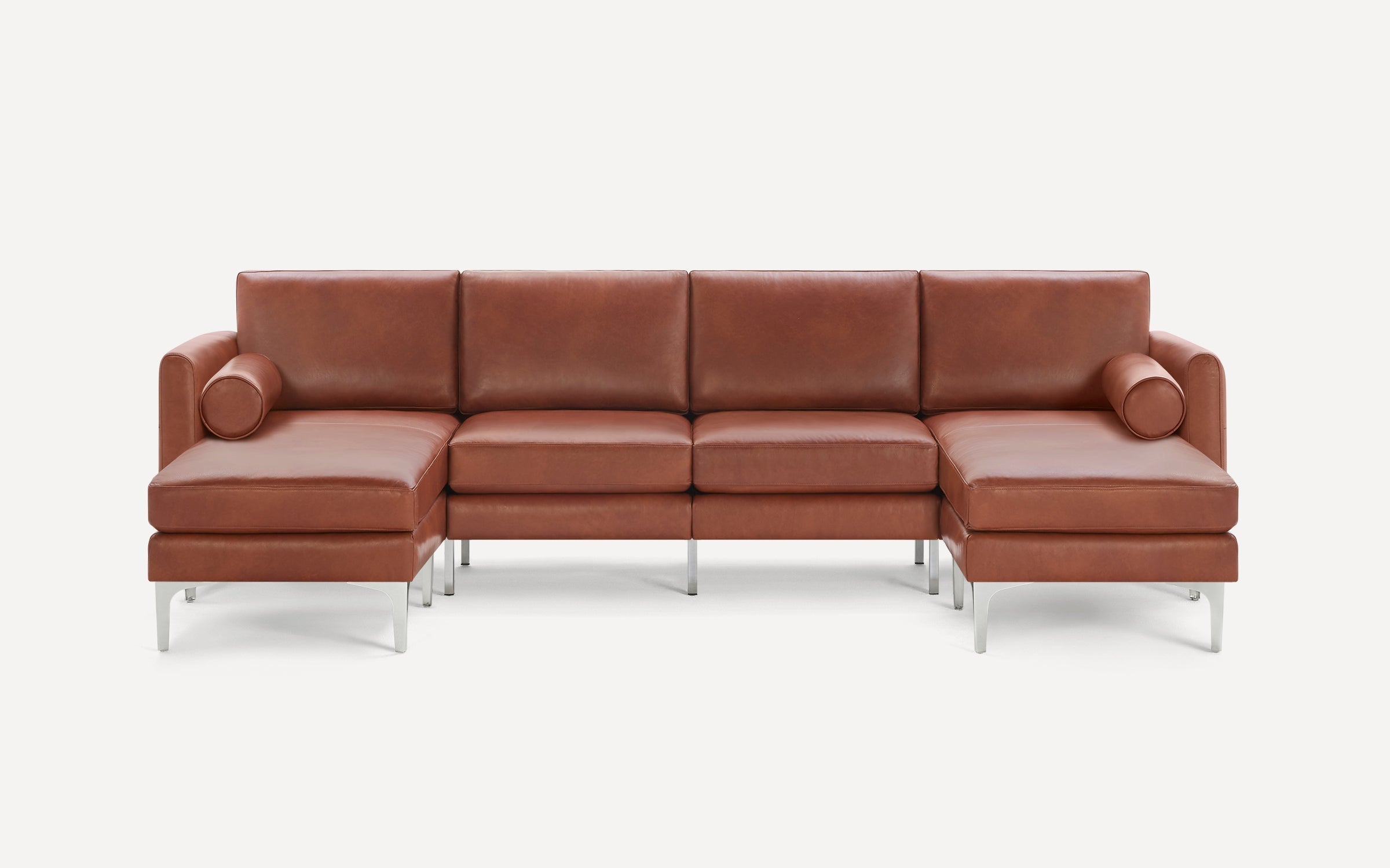 Modern brown leather sectional sofa with clean lines, metal legs, and cylindrical bolster pillows on each end.