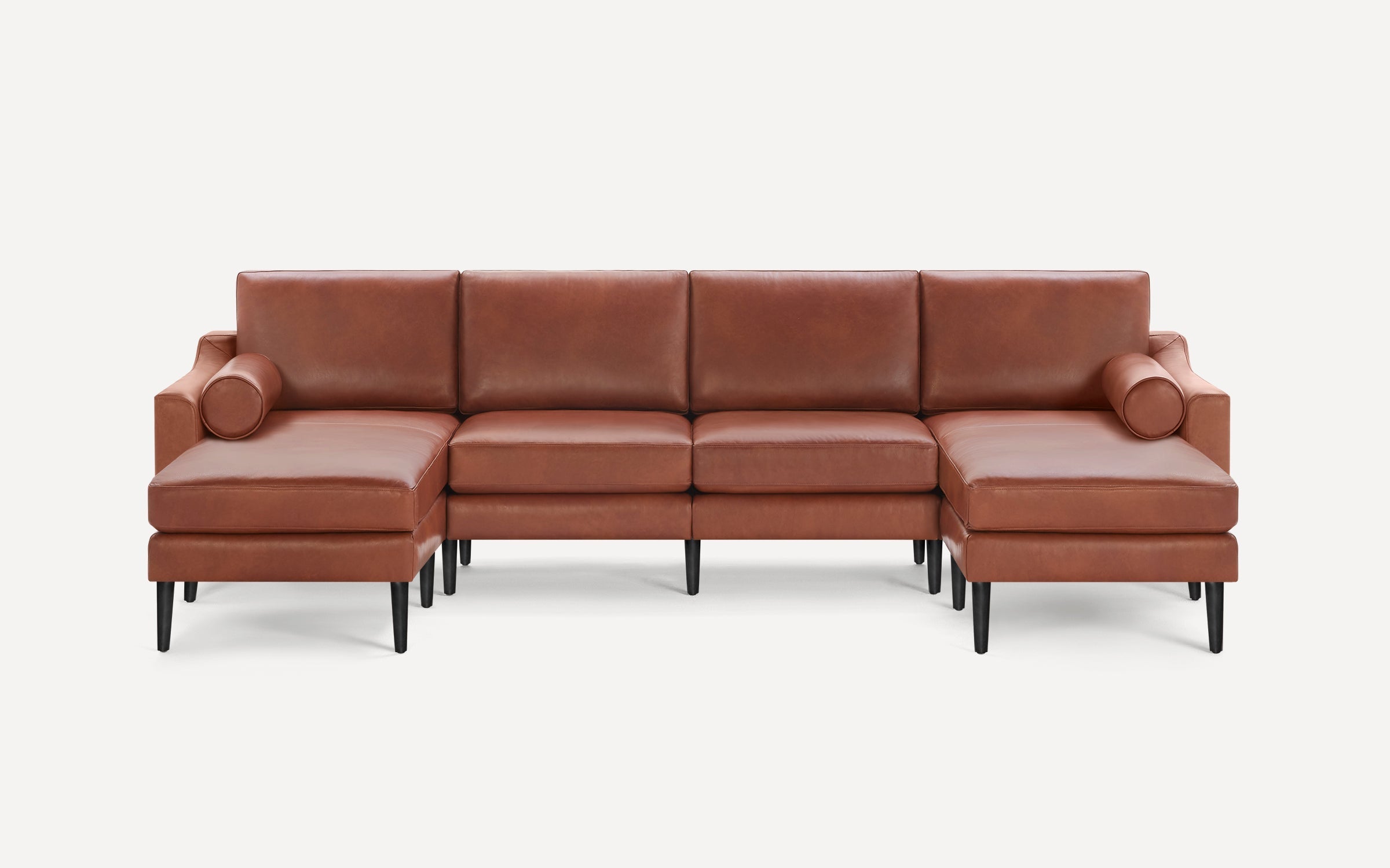 Modern brown leather sectional sofa with chaise lounges on both ends, supported by slender black legs and round bolsters.