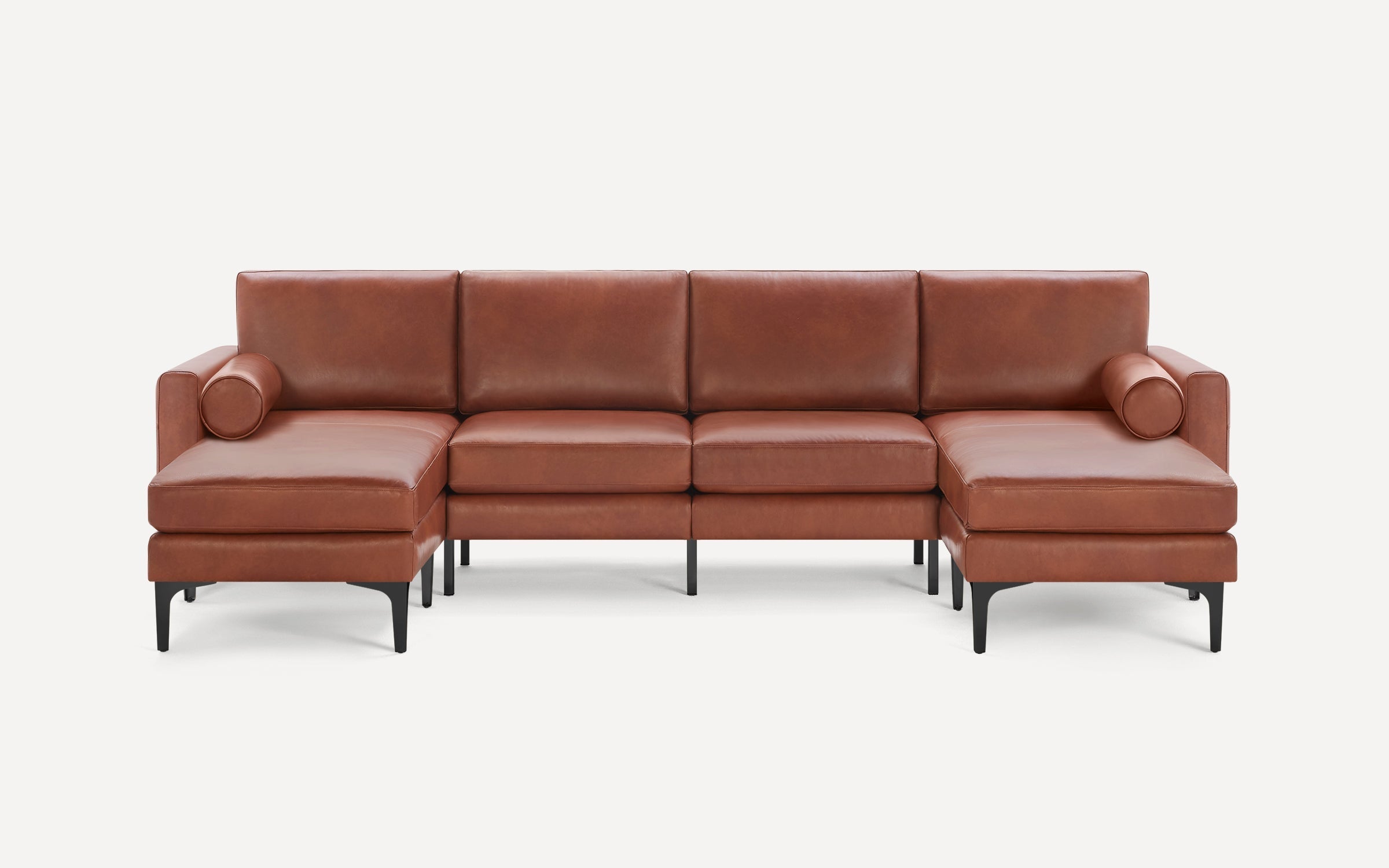 Modern brown leather sectional sofa with chaise lounges on both ends, straight black metal legs, and cylindrical bolster pillows.