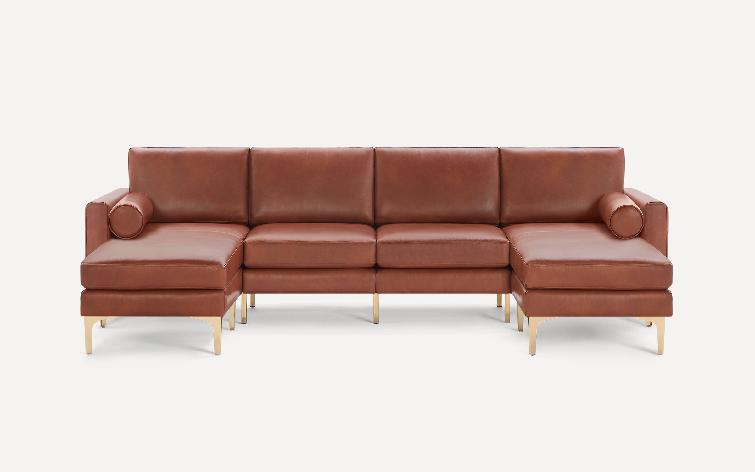 Brown leather sectional sofa with gold metal legs, featuring left and right chaise lounges and cylindrical bolster pillows.