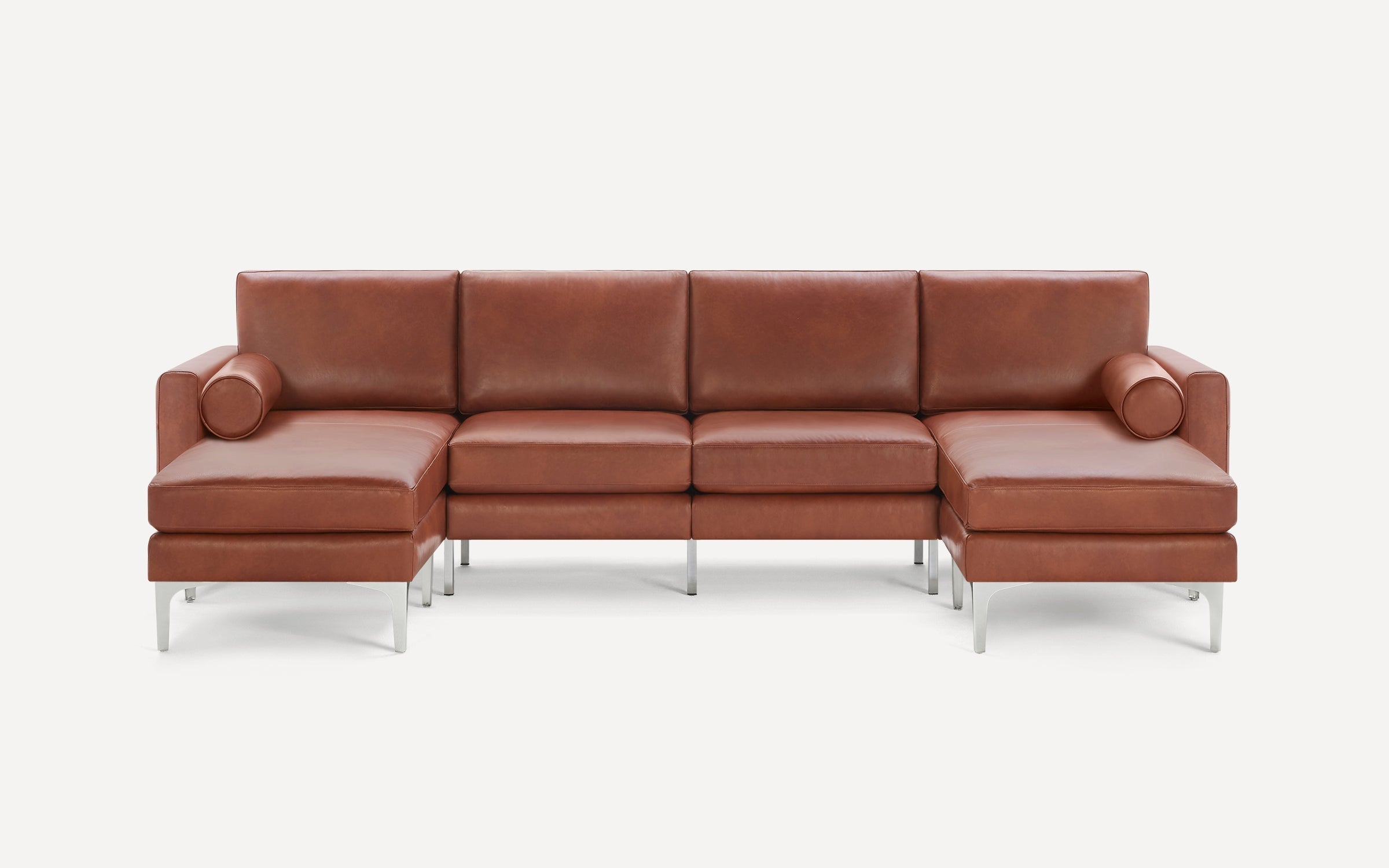 Modern brown leather sectional sofa with clean lines, metal legs, and cylindrical bolster pillows on each end.