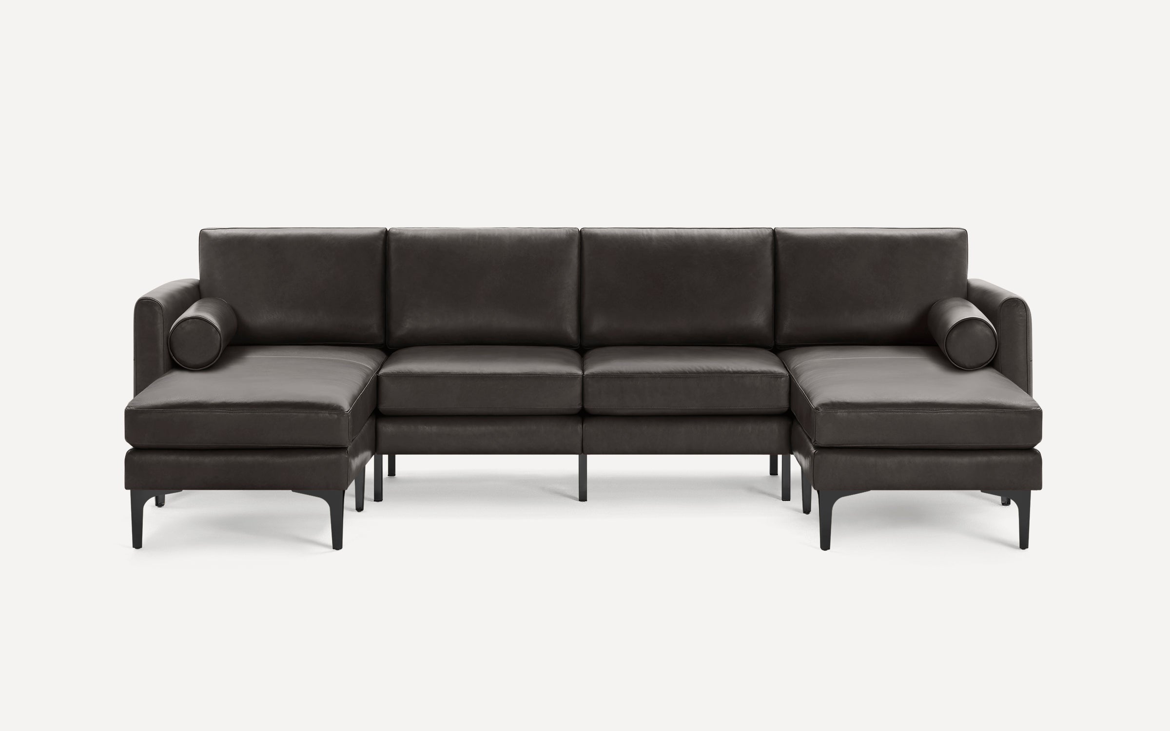 Modern dark brown leather sectional sofa with chaise lounges on both ends and cylindrical bolster pillows.