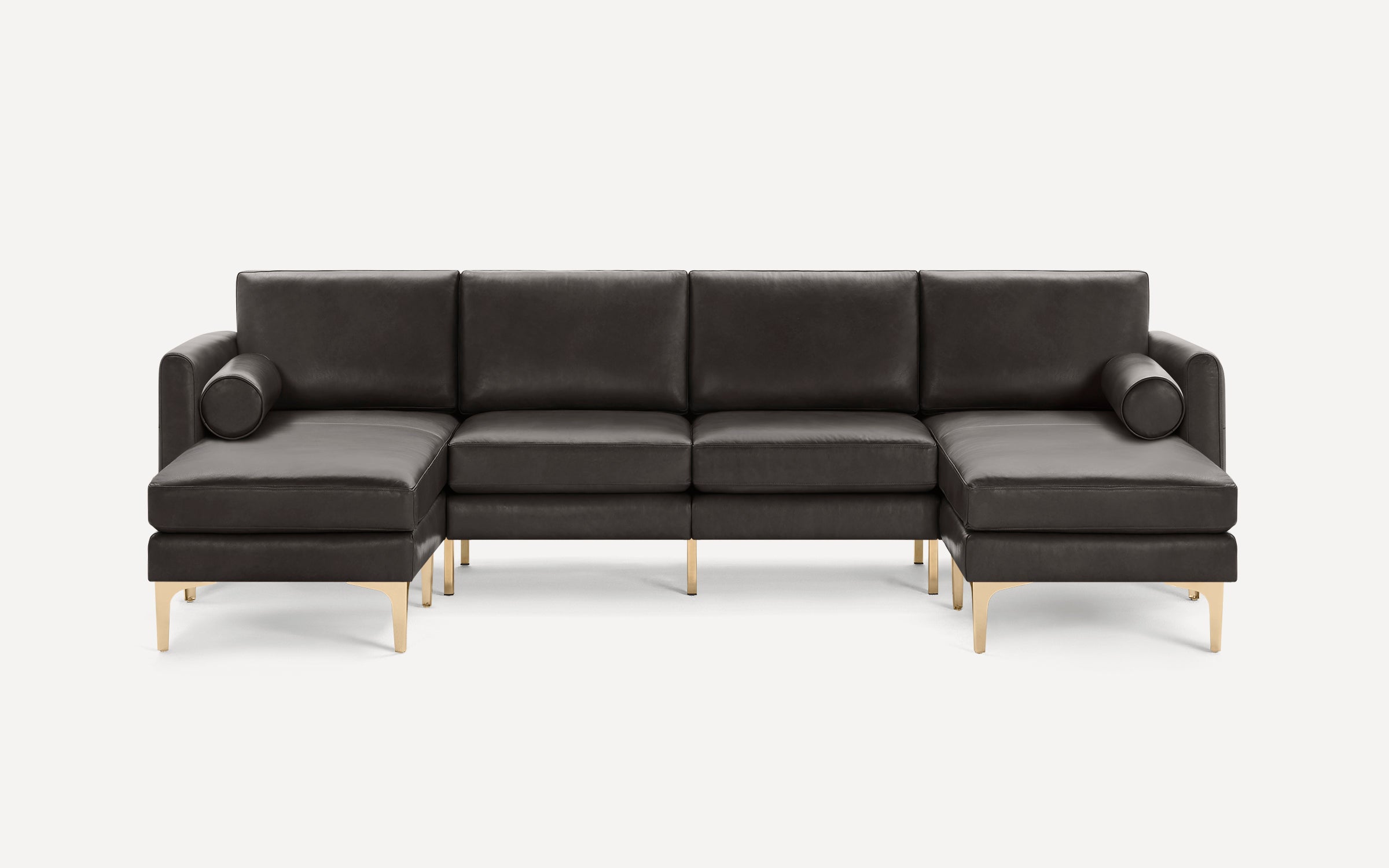 Modern dark gray leather sectional sofa with gold metal legs, featuring two chaise lounges and cylindrical bolster pillows.