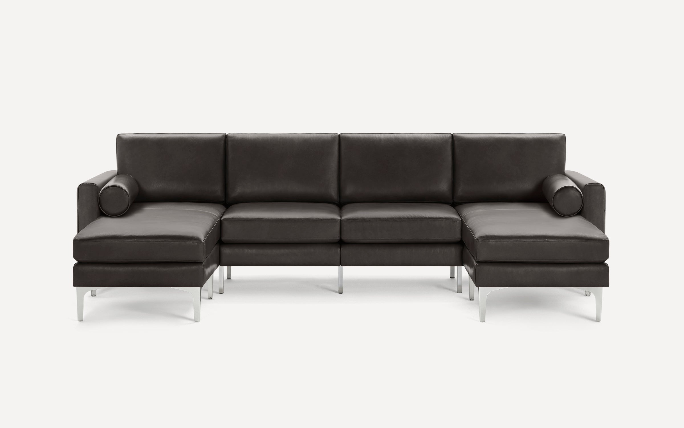 Modern dark gray leather sectional sofa with metal legs, featuring two chaise lounges and cylindrical bolster pillows.