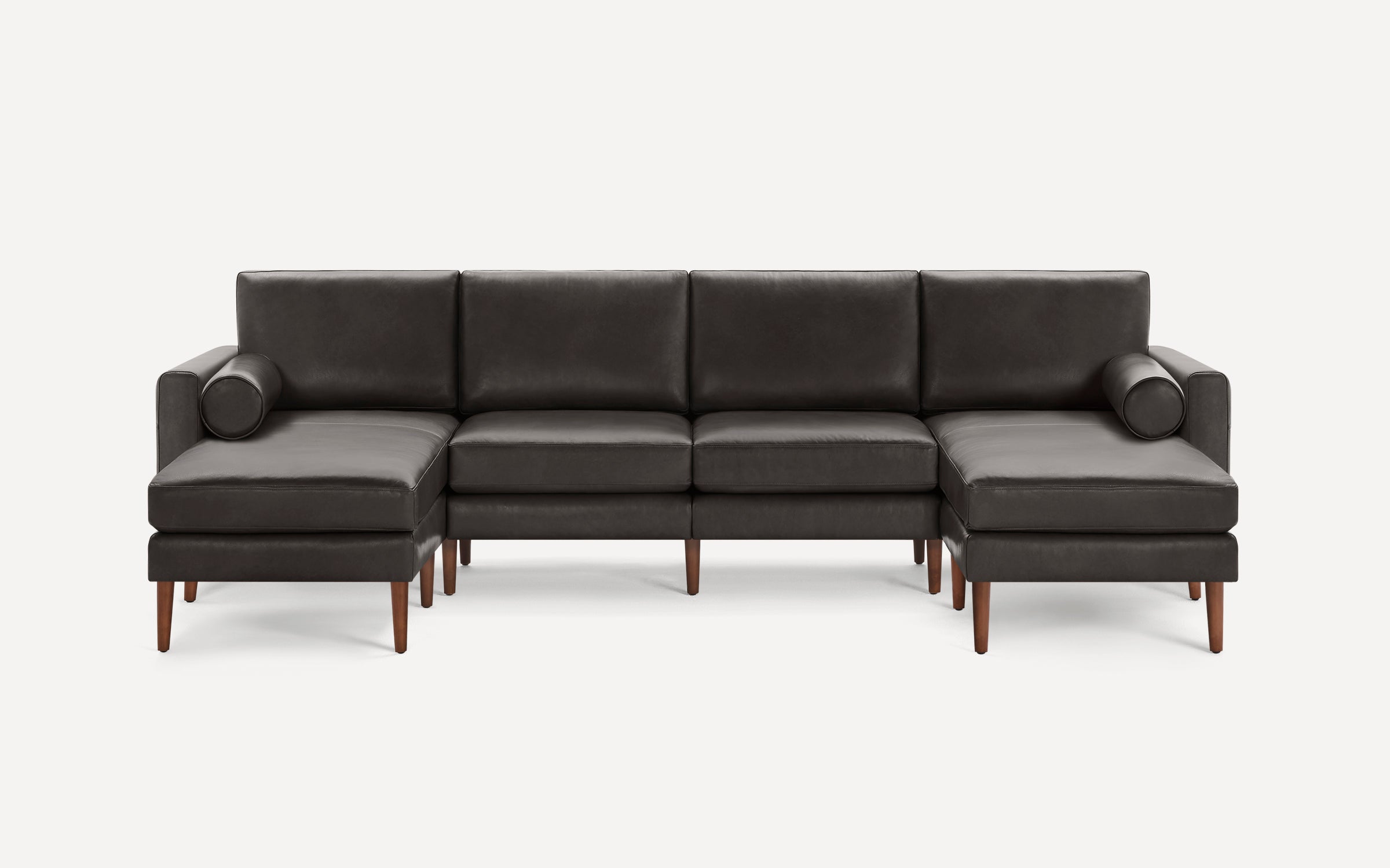 Modern dark gray leather sectional sofa with wooden legs and two cylindrical bolster pillows, featuring left and right chaise lounges.