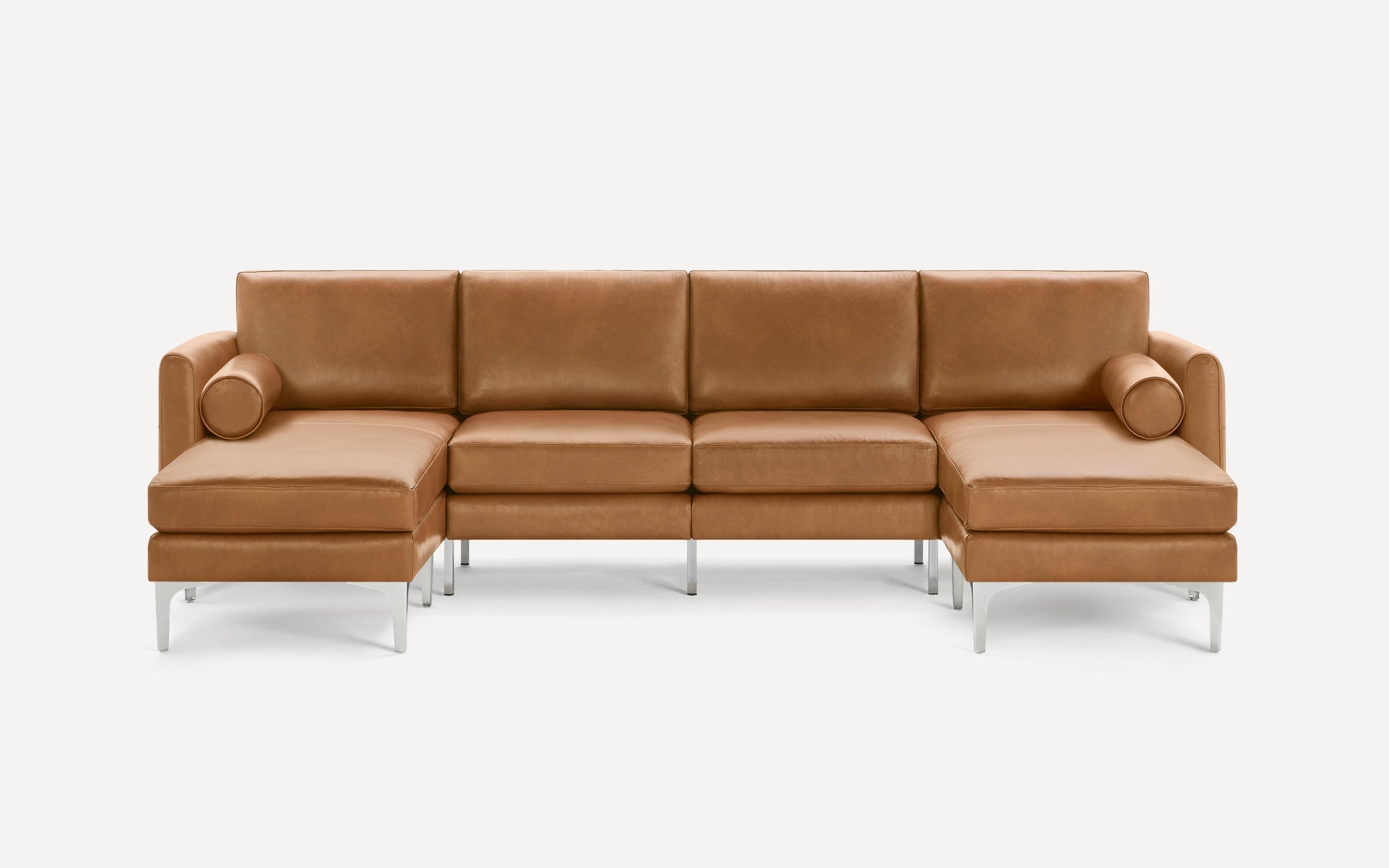 Tan leather sectional sofa with metal legs, two chaise ends, four back cushions, and two round bolster pillows.