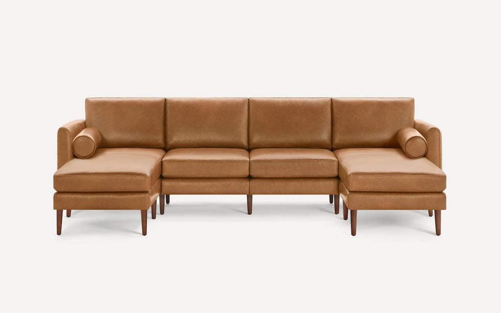 Modern brown leather sectional sofa with clean lines, wooden legs, and two cylindrical bolster pillows on each chaise end.