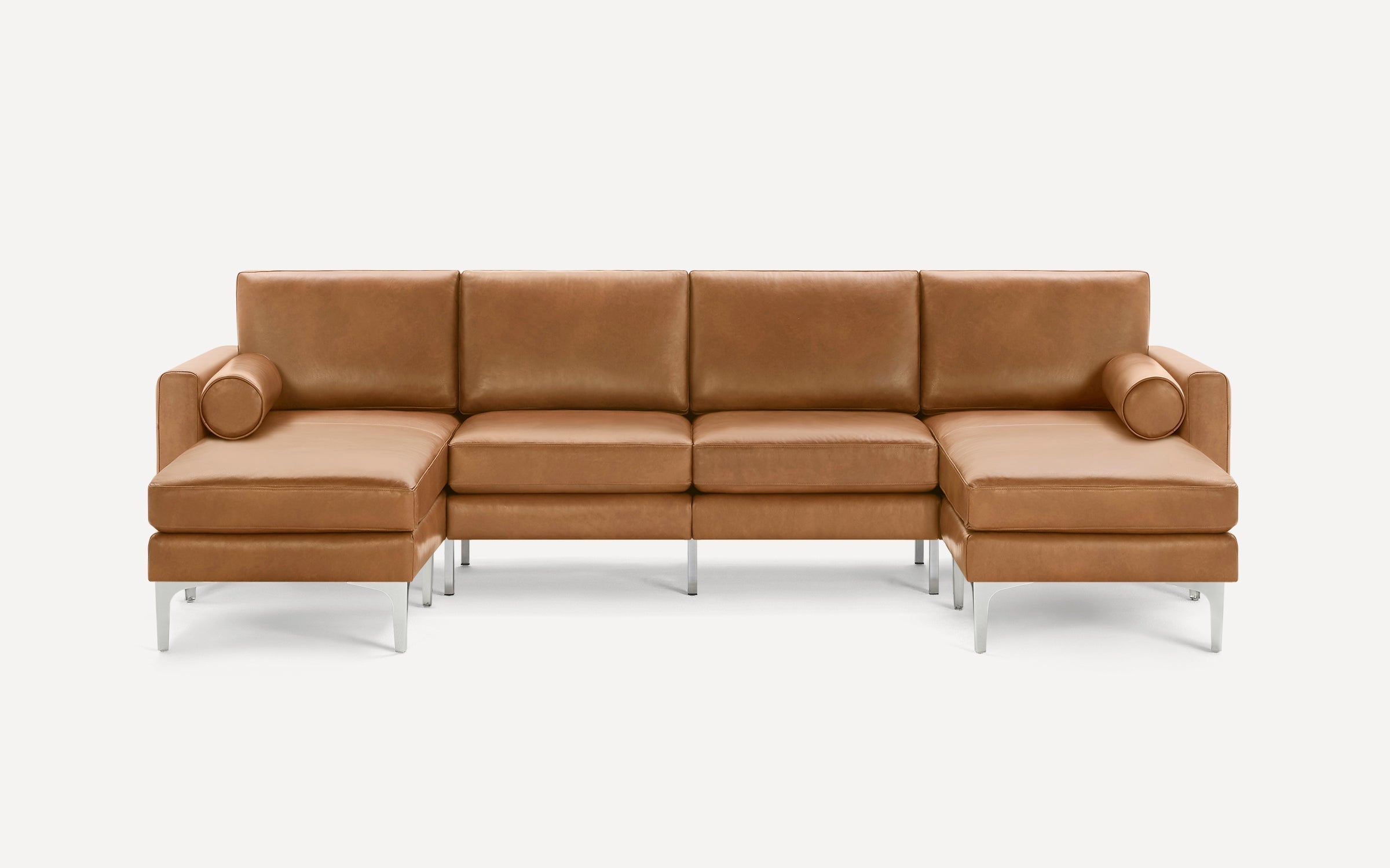 Modern tan leather sectional sofa with metal legs, featuring two chaise lounges and cylindrical bolster pillows on both ends.