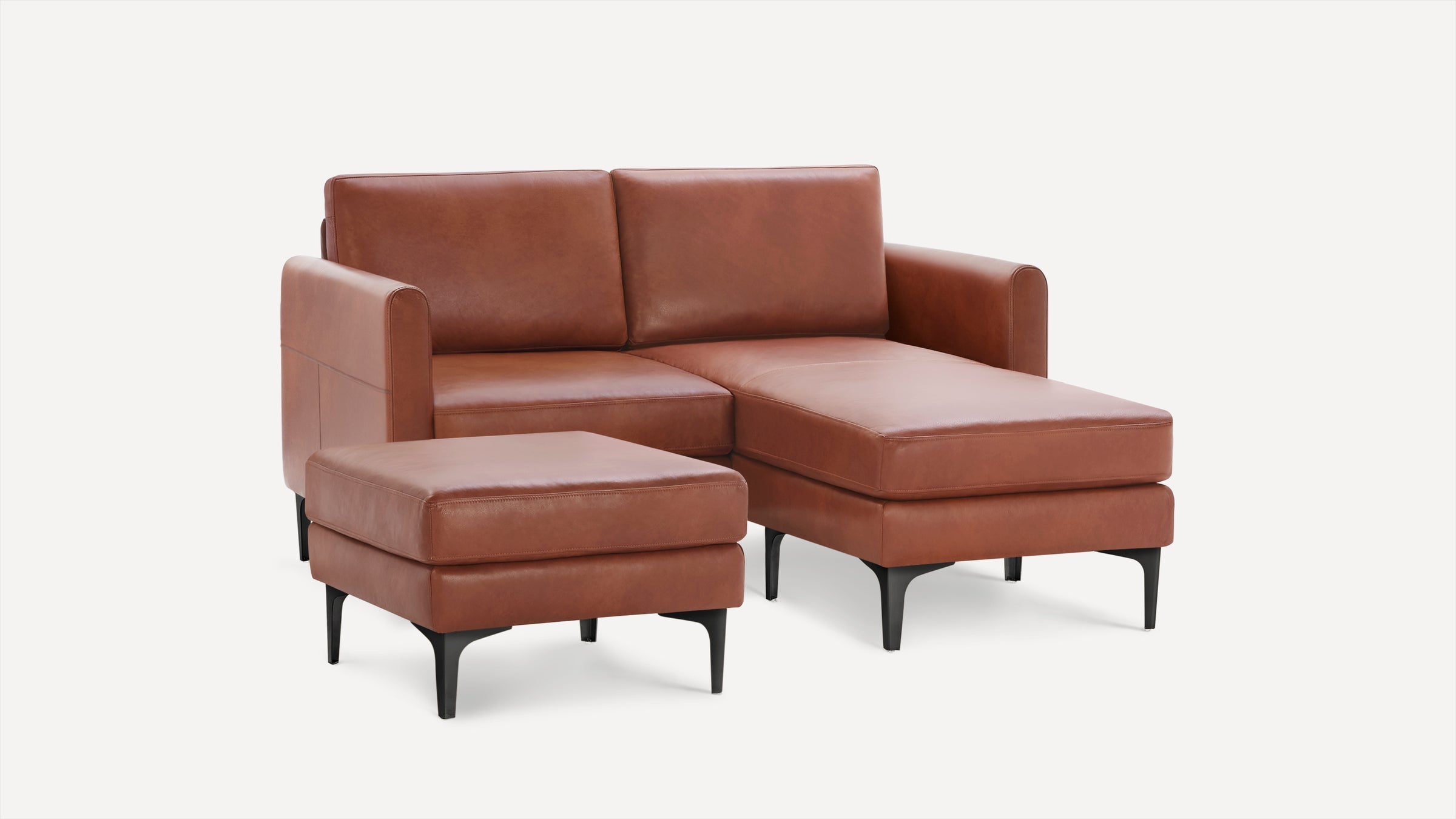 Modern brown leather sectional sofa with chaise lounge and matching ottoman, supported by sleek black legs.