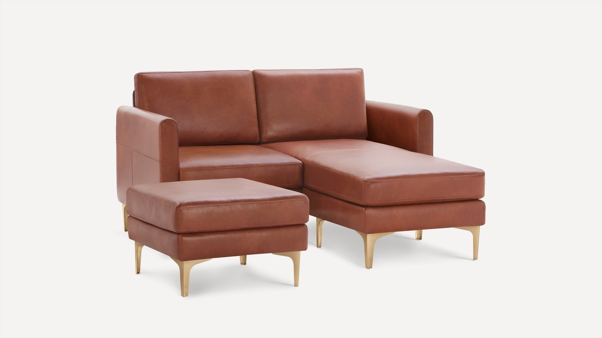 Brown leather sectional sofa with chaise lounge and matching ottoman, featuring sleek gold metal legs.