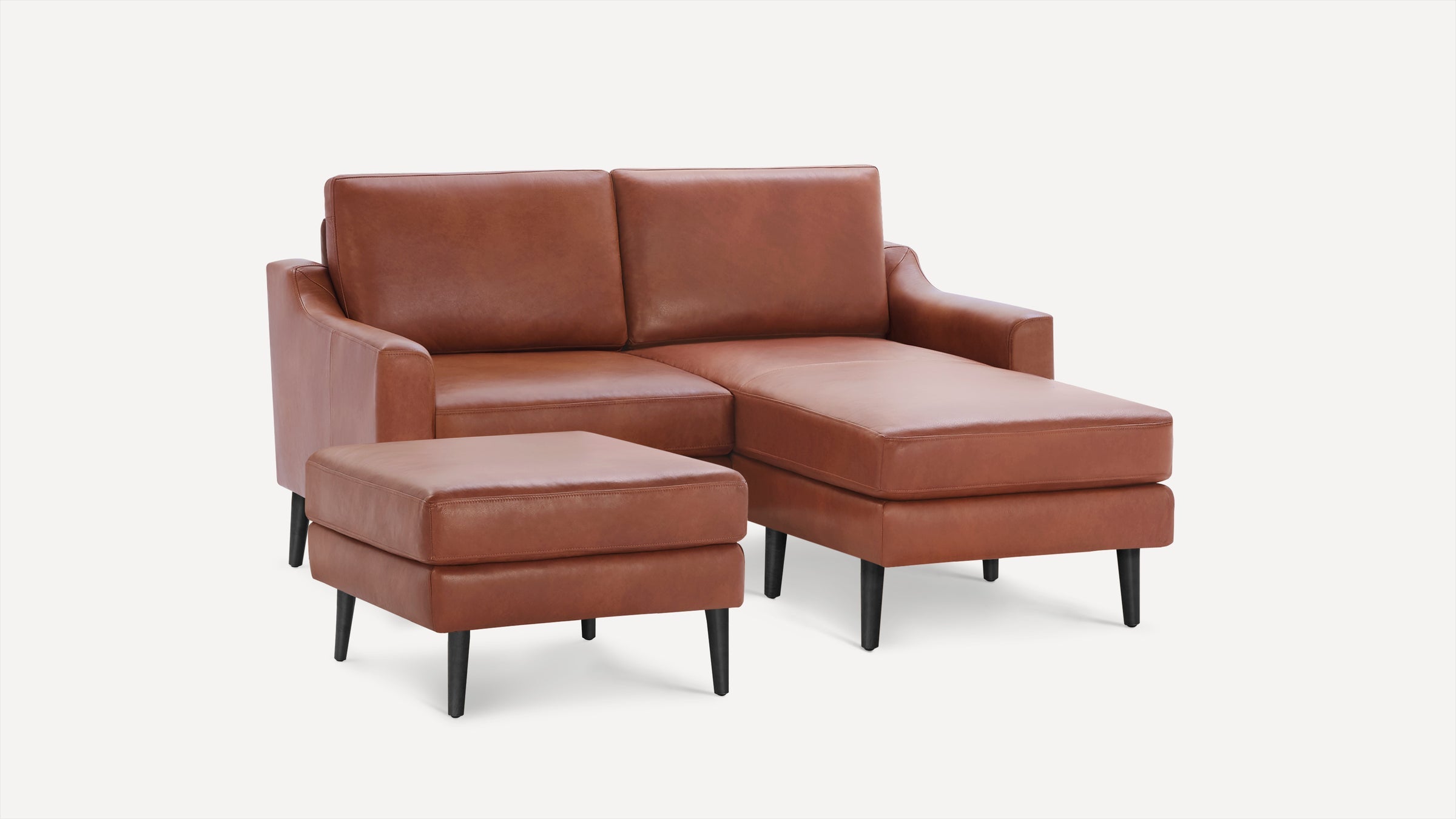 Brown leather sectional sofa with chaise lounge and matching ottoman, featuring black tapered legs and clean modern design.
