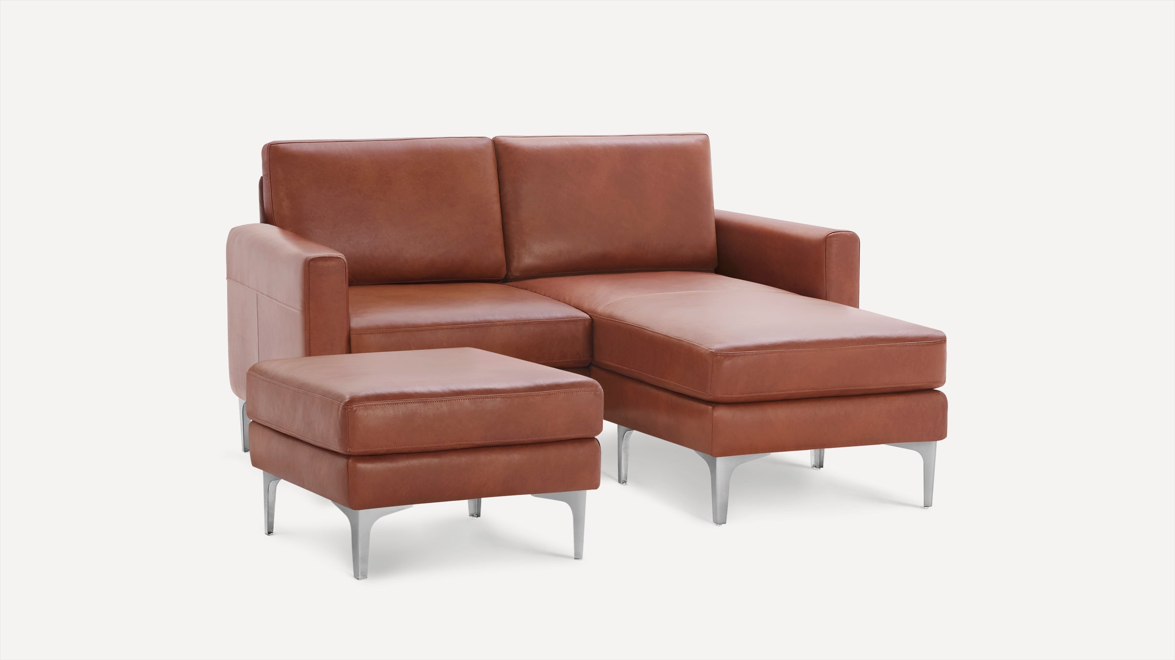 Modern brown leather sectional sofa with chaise lounge and matching ottoman, supported by sleek silver metal legs.