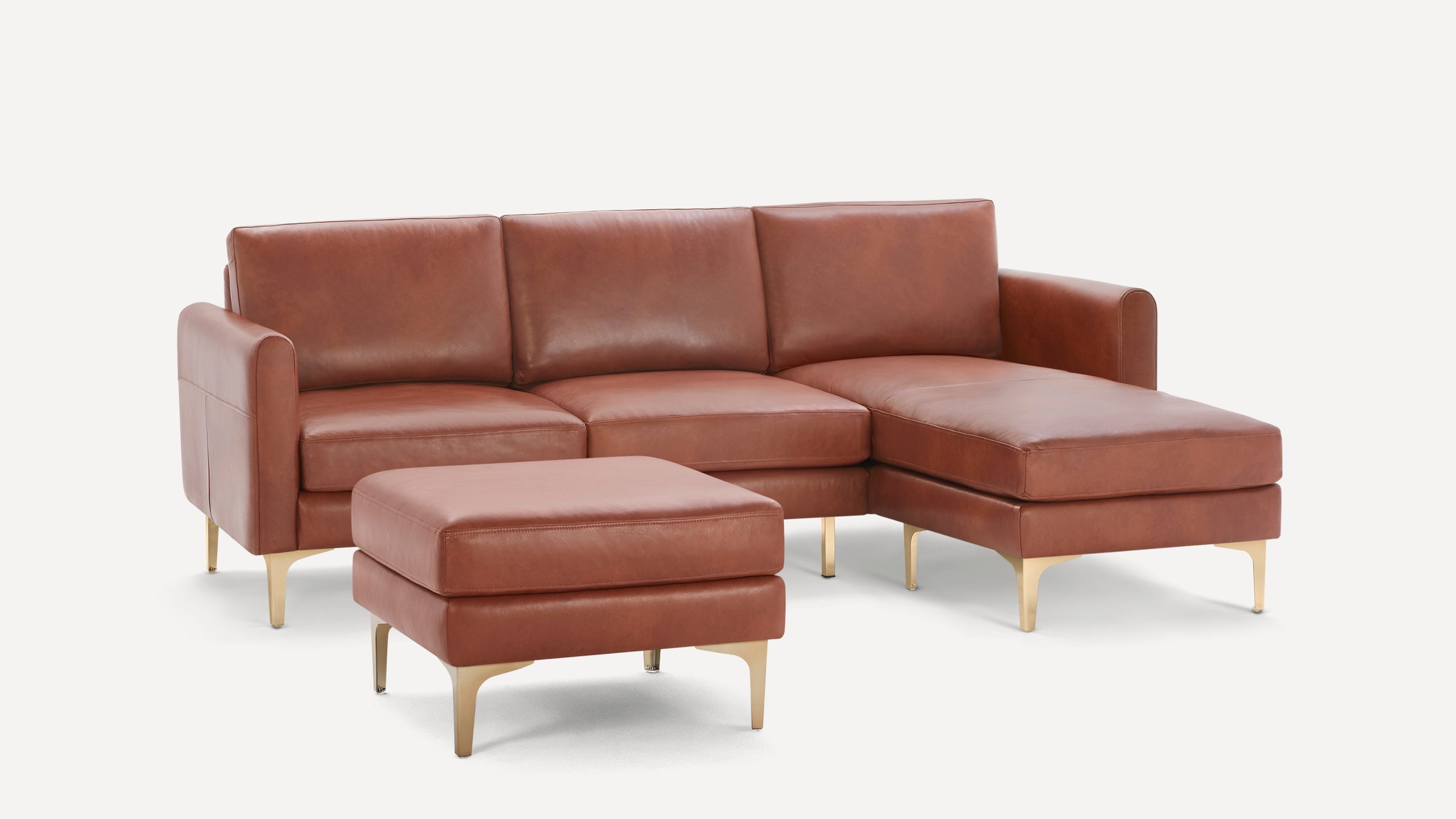 Modern brown leather sectional sofa with chaise lounge and matching ottoman, featuring gold metal legs and clean lines.