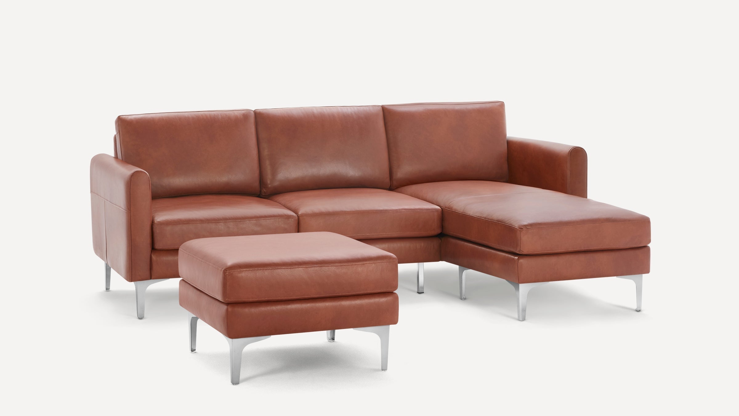 Modern brown leather sectional sofa with chaise lounge and matching ottoman, supported by sleek silver metal legs.