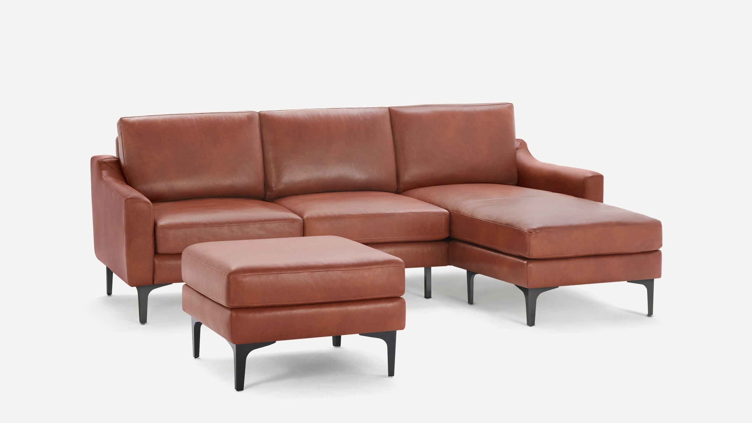 Brown leather sectional sofa with chaise lounge and matching ottoman, featuring sleek black legs and cushioned seating.