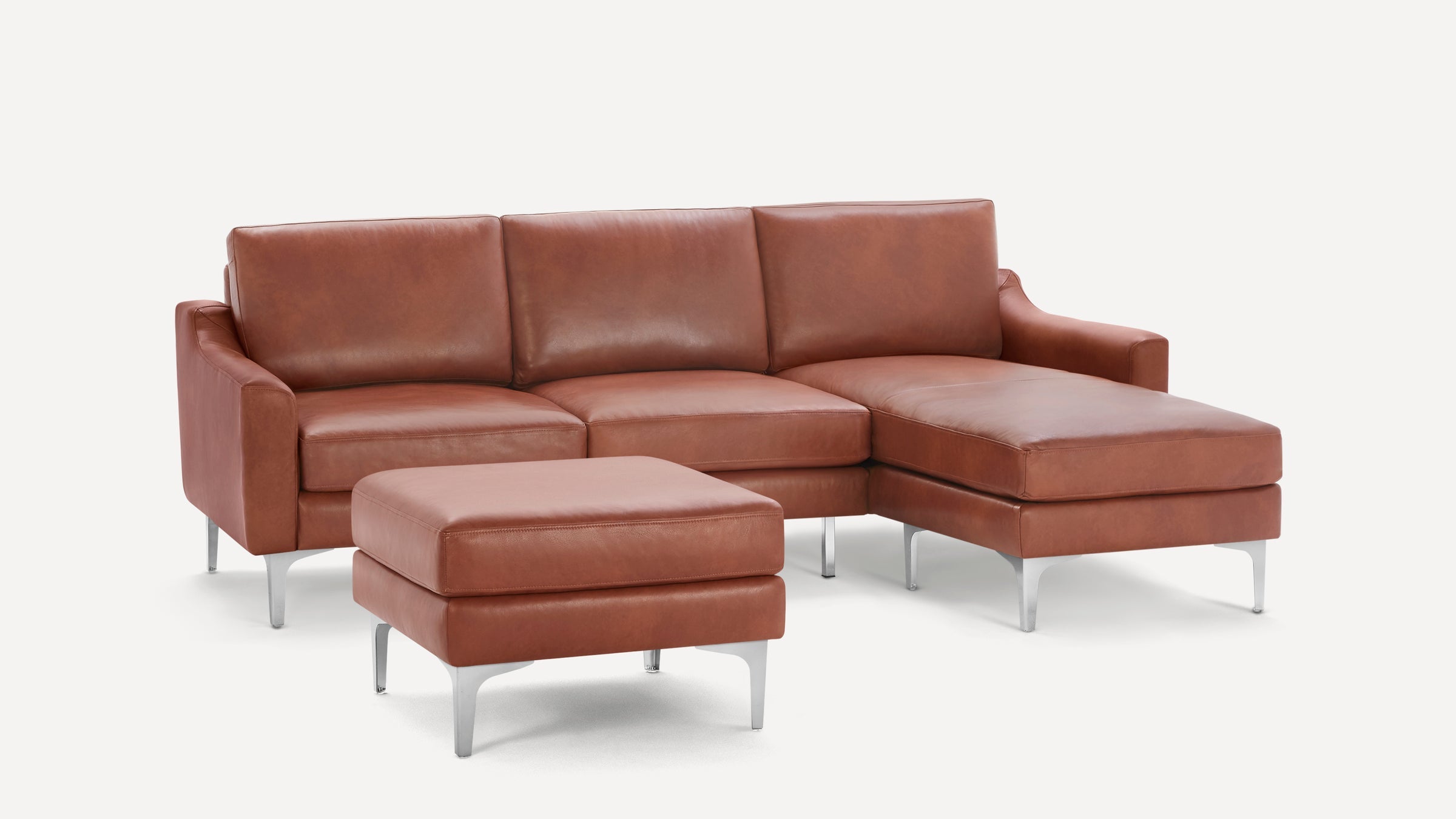 Modern brown leather sectional sofa with chaise and matching ottoman, featuring sleek metal legs and plush cushions.