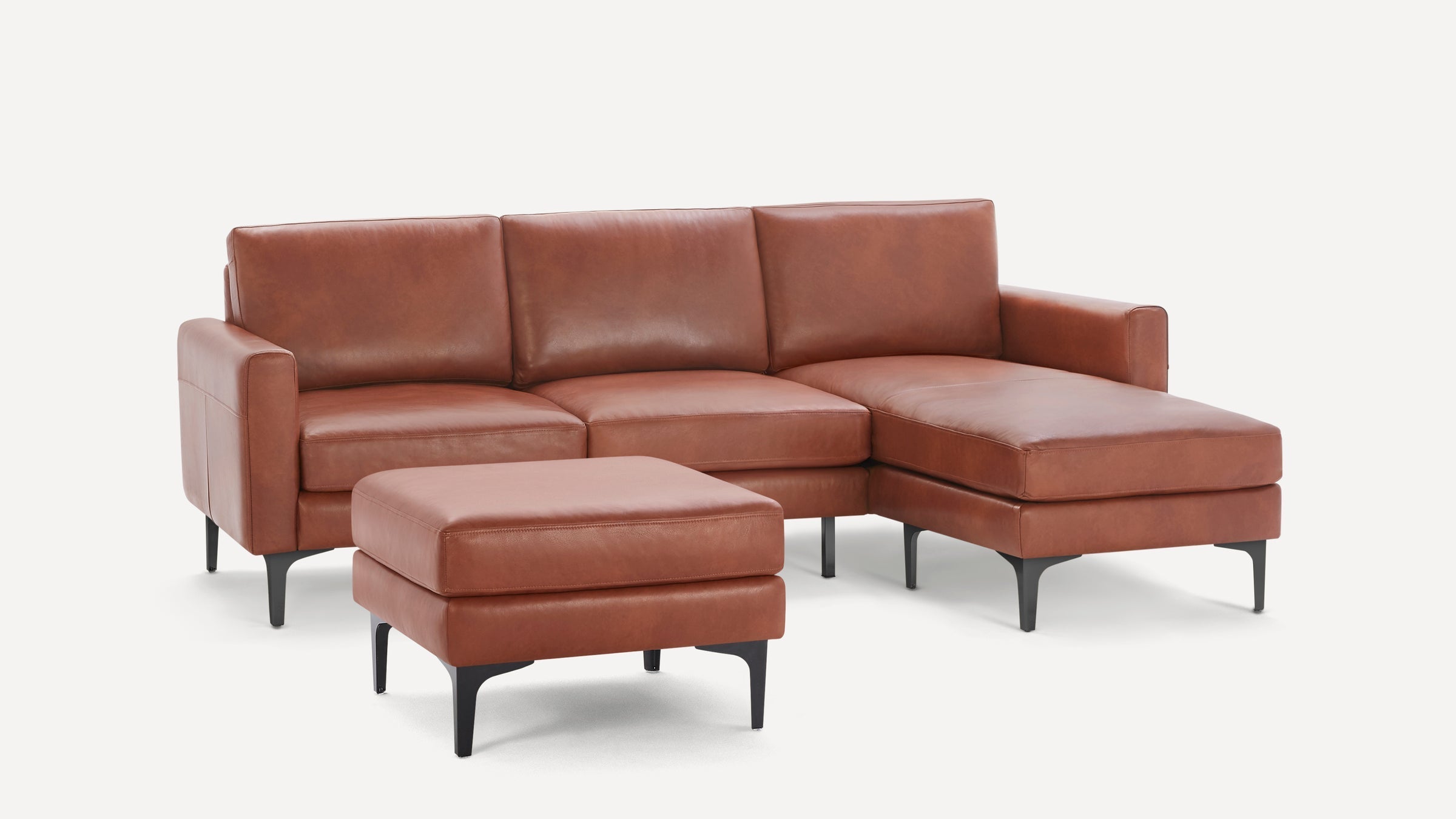 Modern brown leather sectional sofa with chaise lounge and matching ottoman, featuring black metal legs.