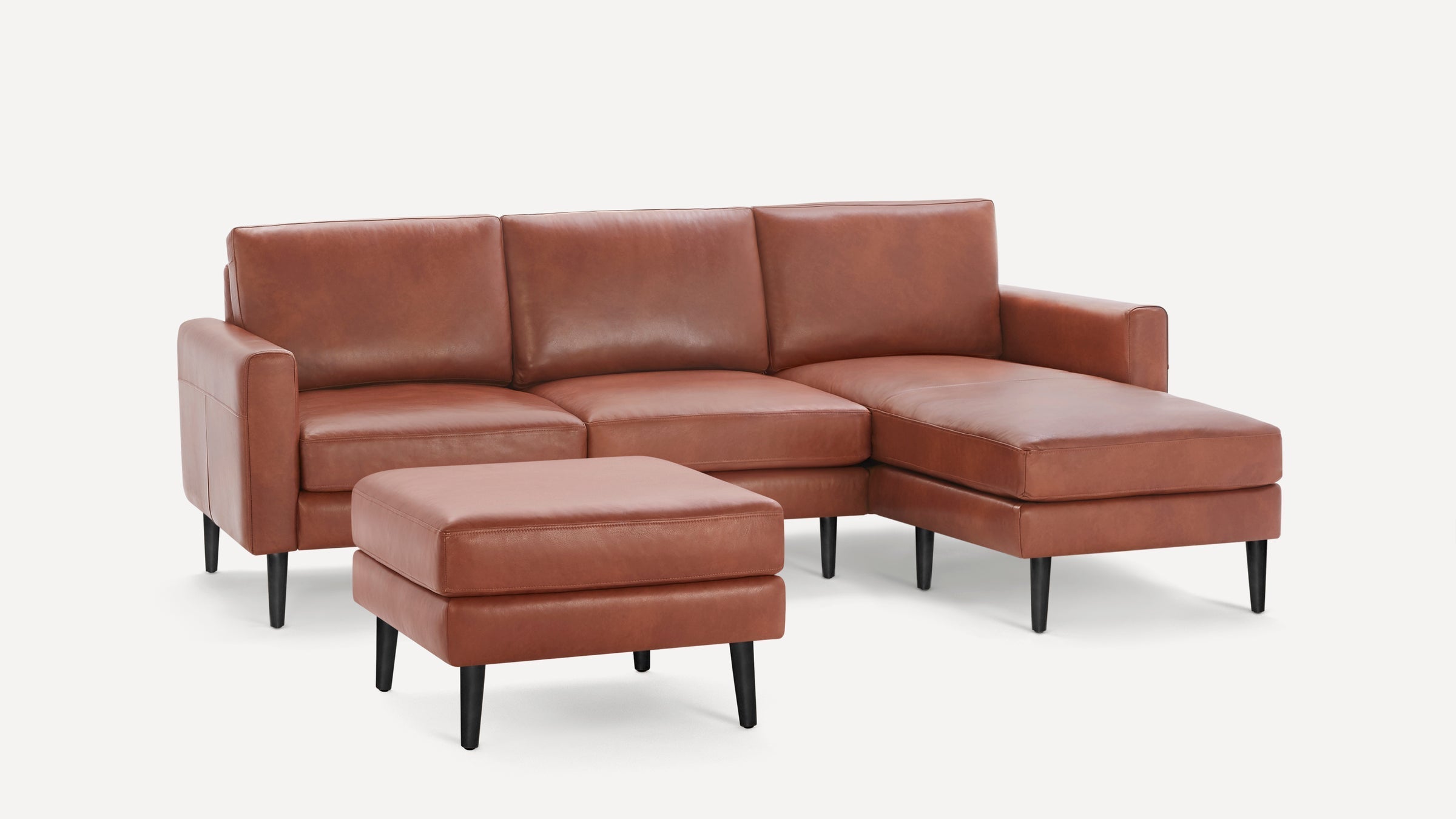 Modern sectional sofa with chaise lounge and matching ottoman, upholstered in smooth brown leather with black tapered legs.