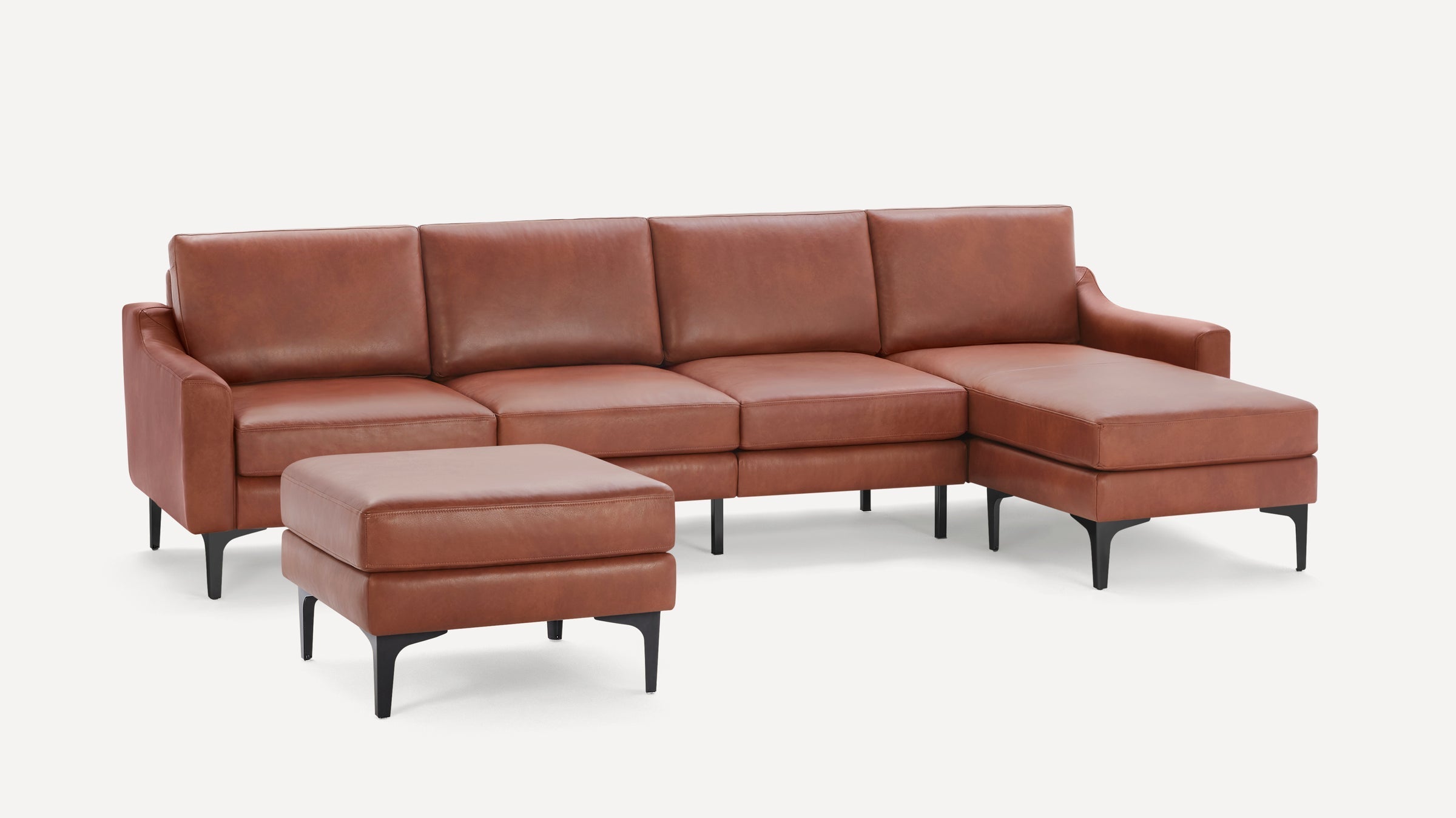 Modern sectional sofa with chaise lounge and matching ottoman, upholstered in smooth brown leather with black legs.