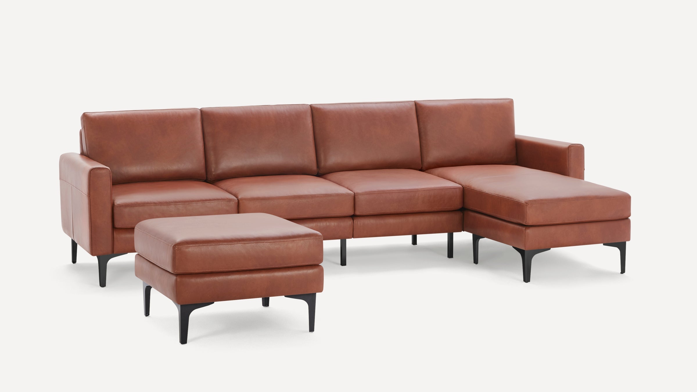 Brown leather sectional sofa with matching ottoman, black angled legs, clean modern design, and wide seating cushions.