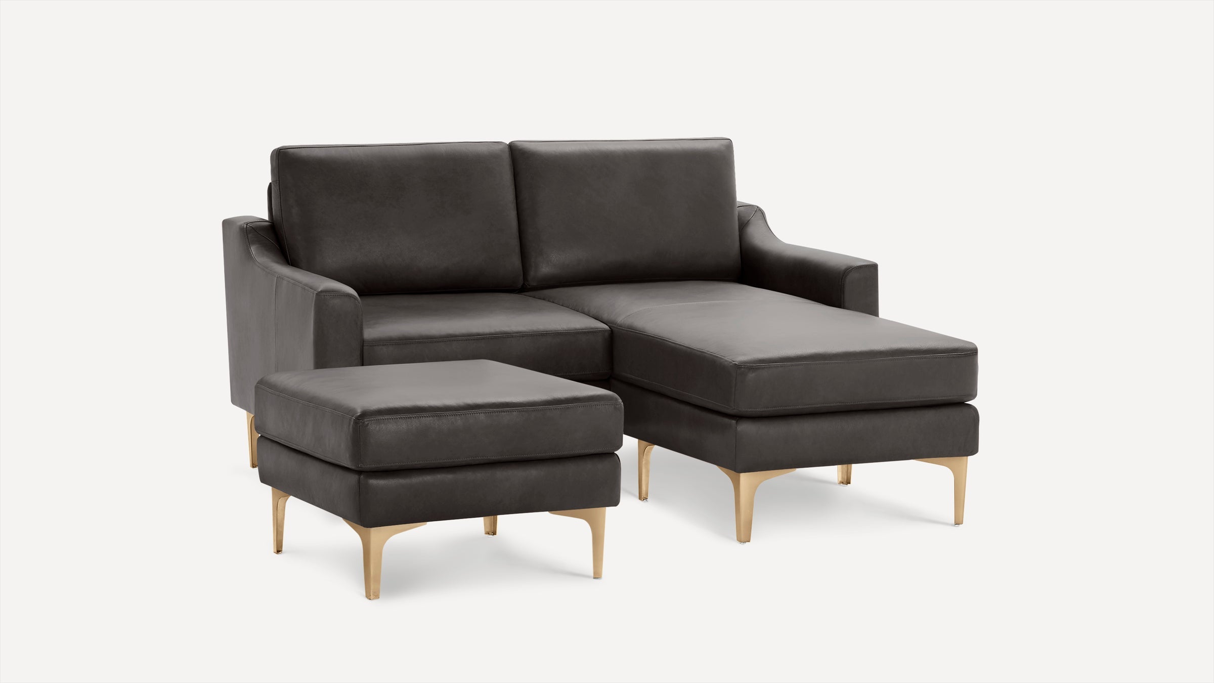 Dark gray leather sectional sofa with a matching ottoman, featuring gold metal legs and clean, modern design.