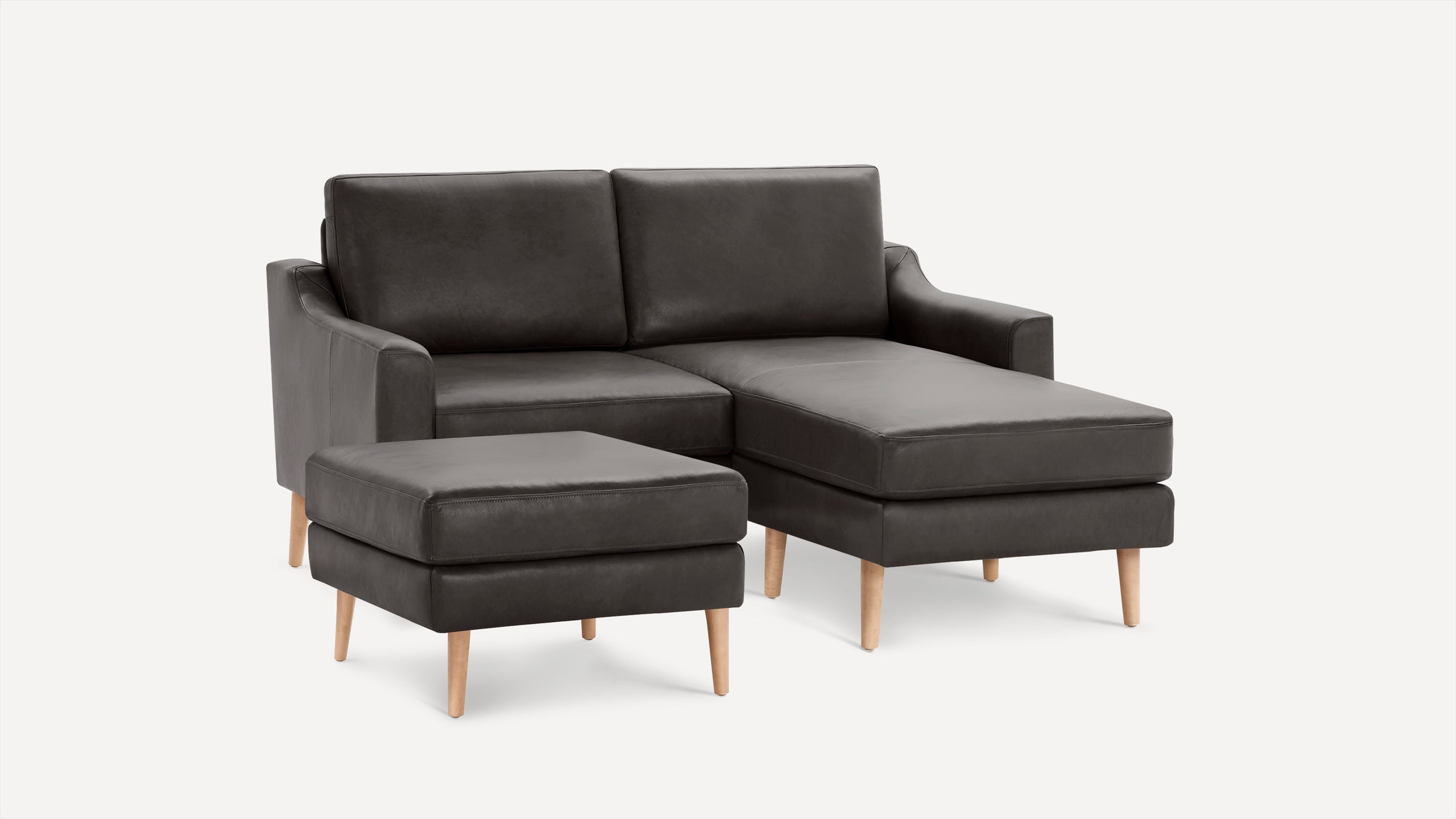 Dark gray modern sectional sofa with chaise lounge and matching ottoman, featuring wooden legs and minimalist design.