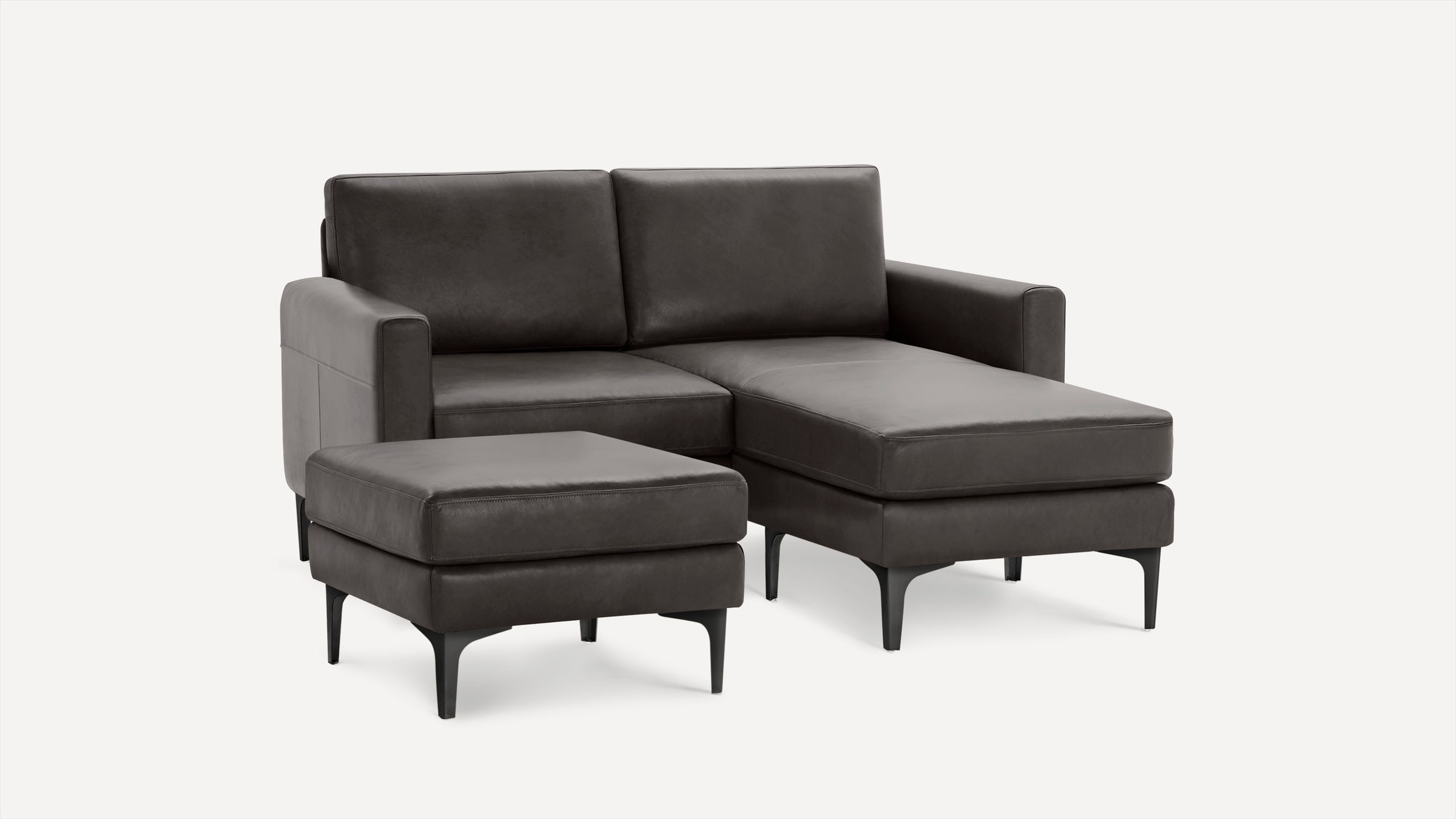 Dark gray modern sectional sofa with chaise lounge and matching ottoman, featuring sleek black legs and smooth upholstery.