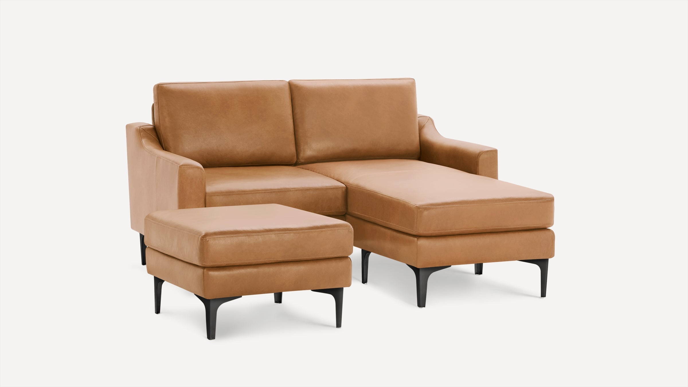 Modern tan leather sectional sofa with chaise lounge and matching ottoman, featuring black tapered legs.