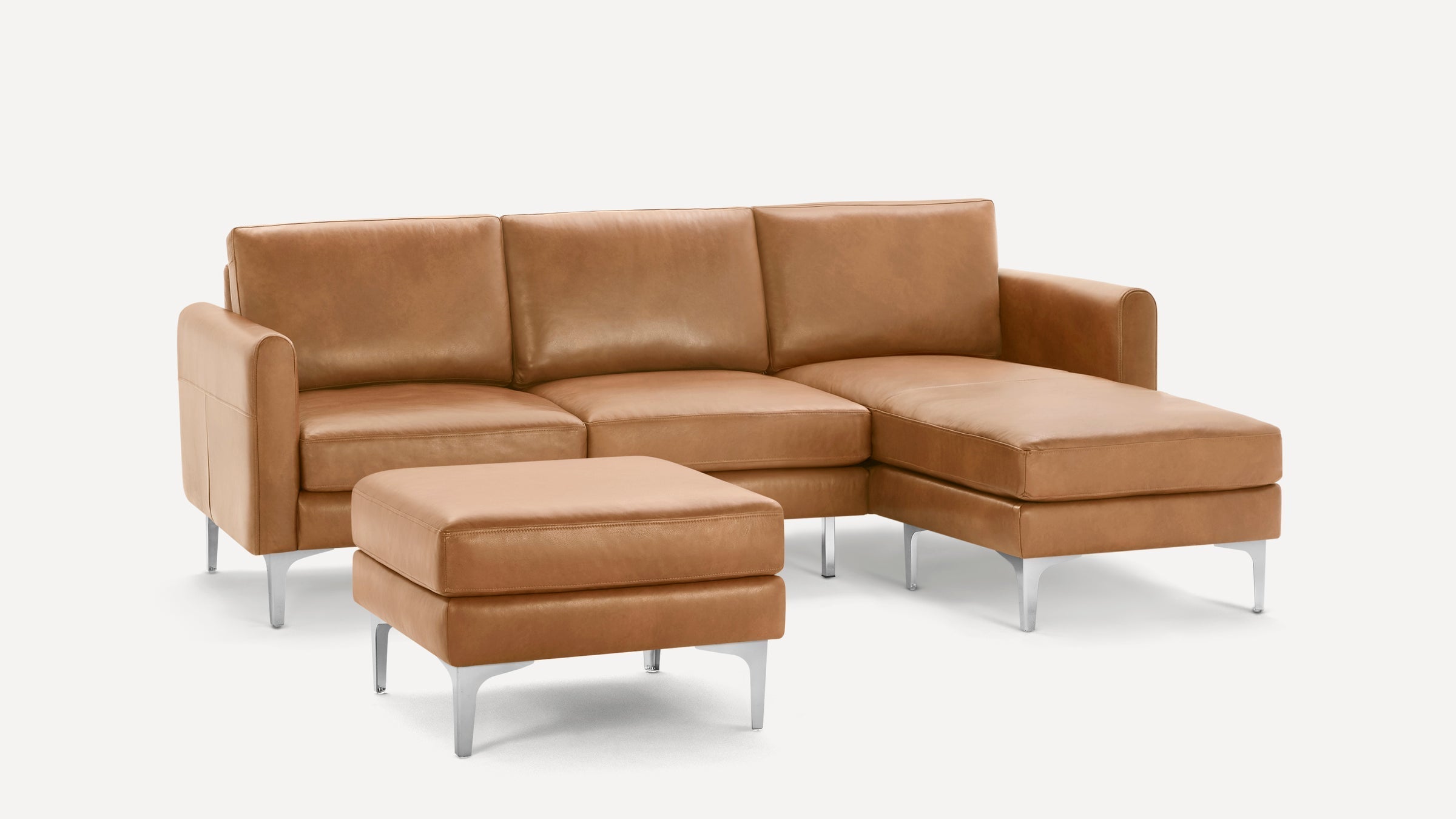 Modern tan leather sectional sofa with chaise lounge and matching ottoman, featuring sleek metal legs and clean lines.