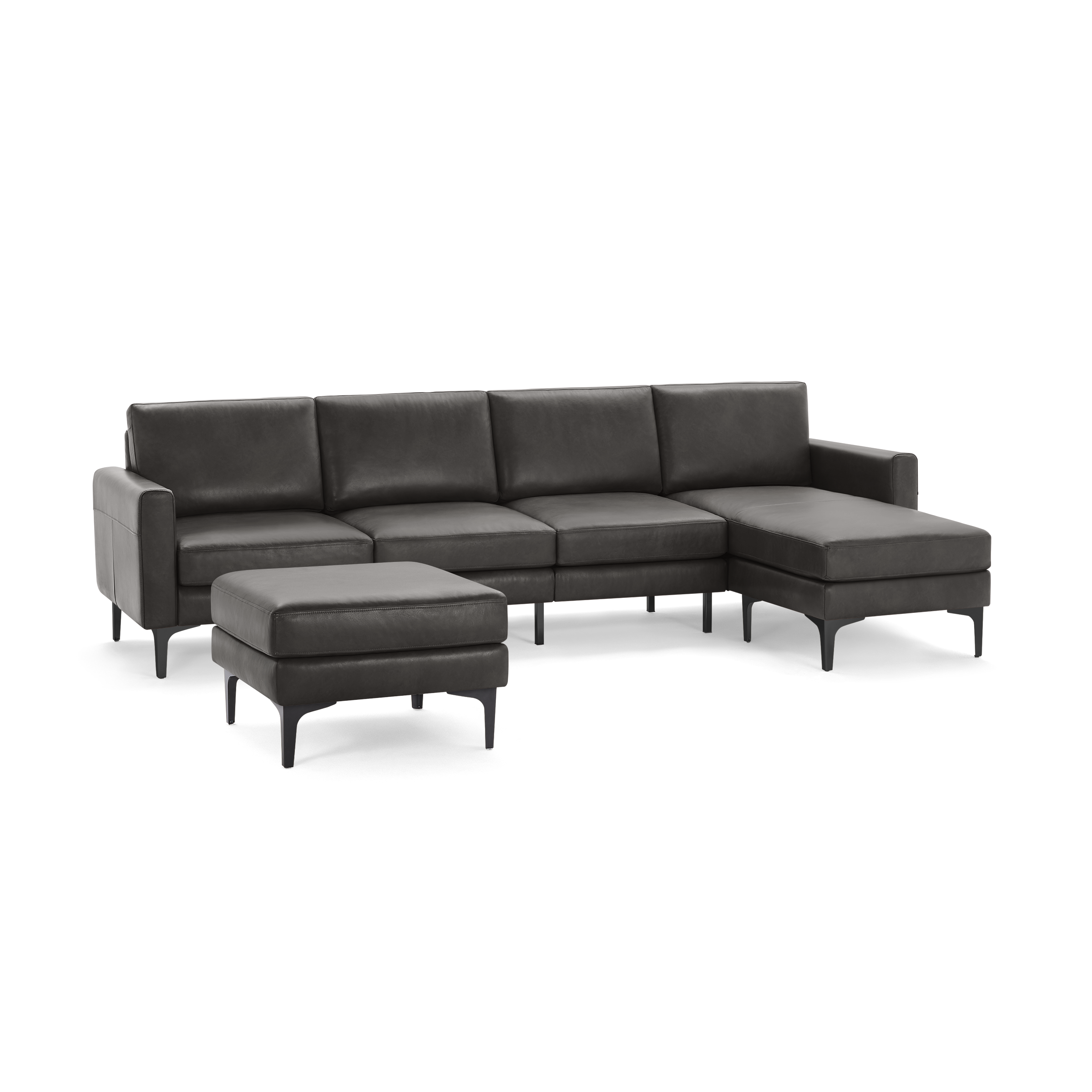 Dark gray leather sectional sofa with chaise lounge on right side and matching ottoman, supported by slender black legs.