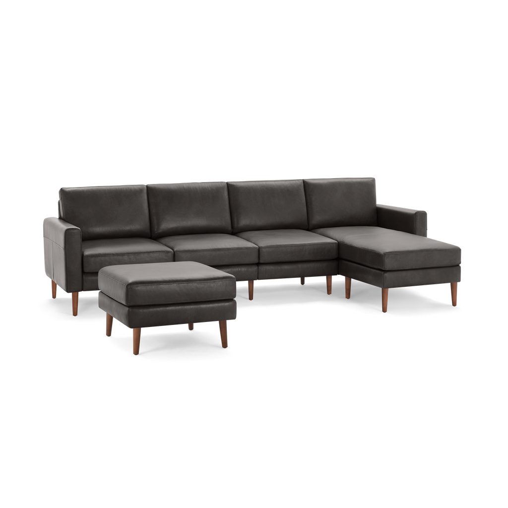 Dark gray modern sectional sofa with wooden legs and matching ottoman, featuring clean lines and cushioned seats.
