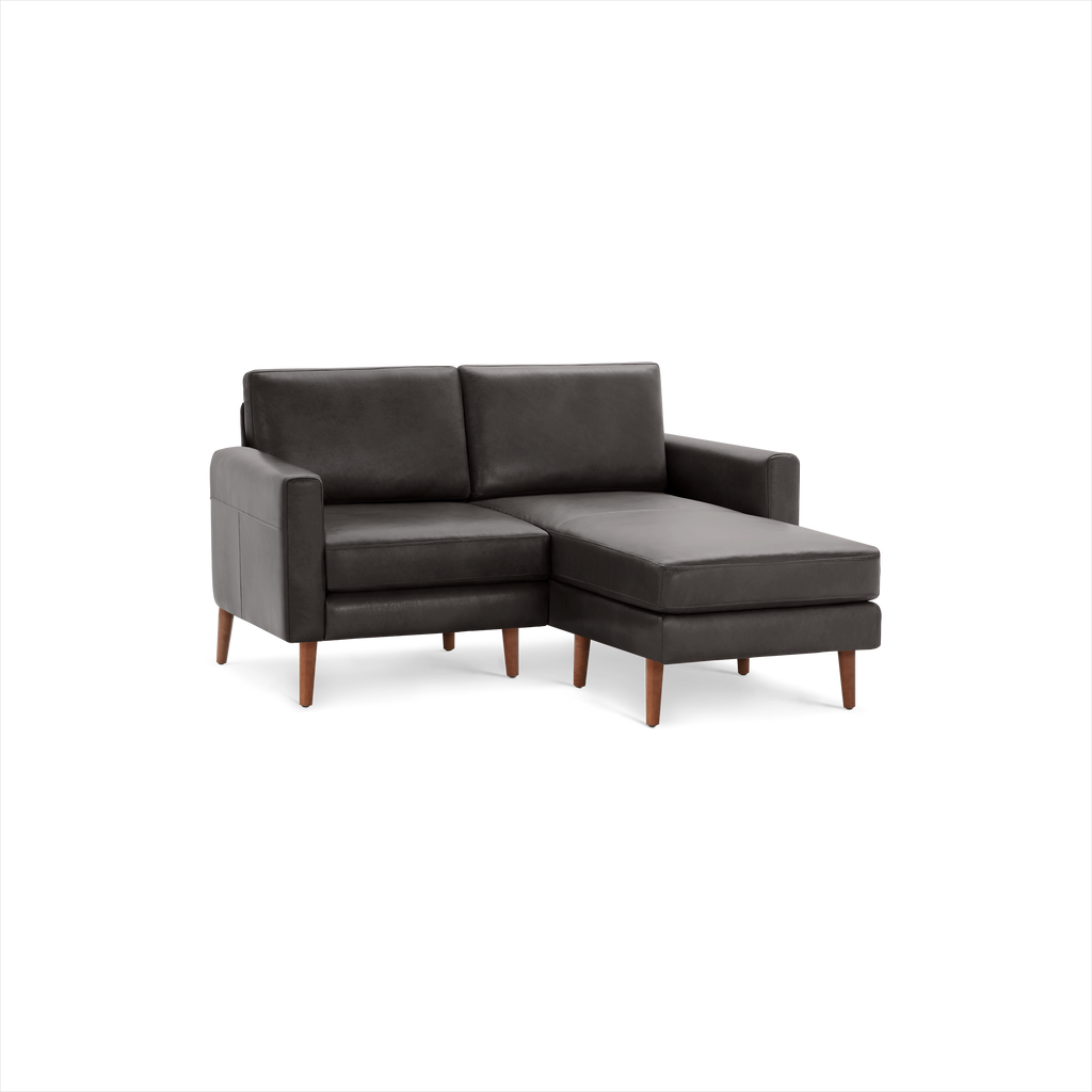 Modern dark gray leather sectional sofa with wooden legs and chaise lounge on right side, designed for compact spaces.