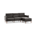 Dark gray leather sectional sofa with three cushions and wooden legs, featuring a chaise lounge on the right side.