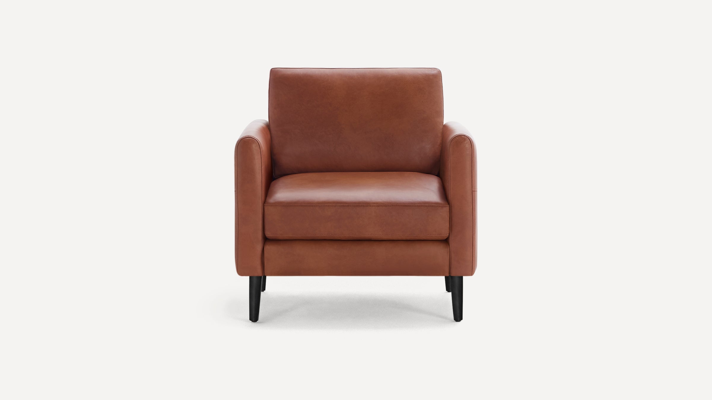 Front view of a modern, brown leather armchair with black tapered legs on a white background.